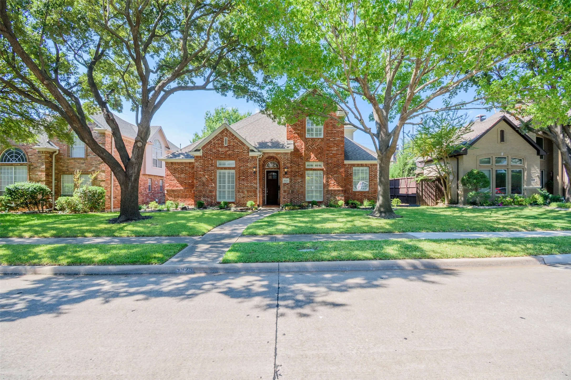Red brick exterior with white shutter accents, arched entryway, and a gabled roof