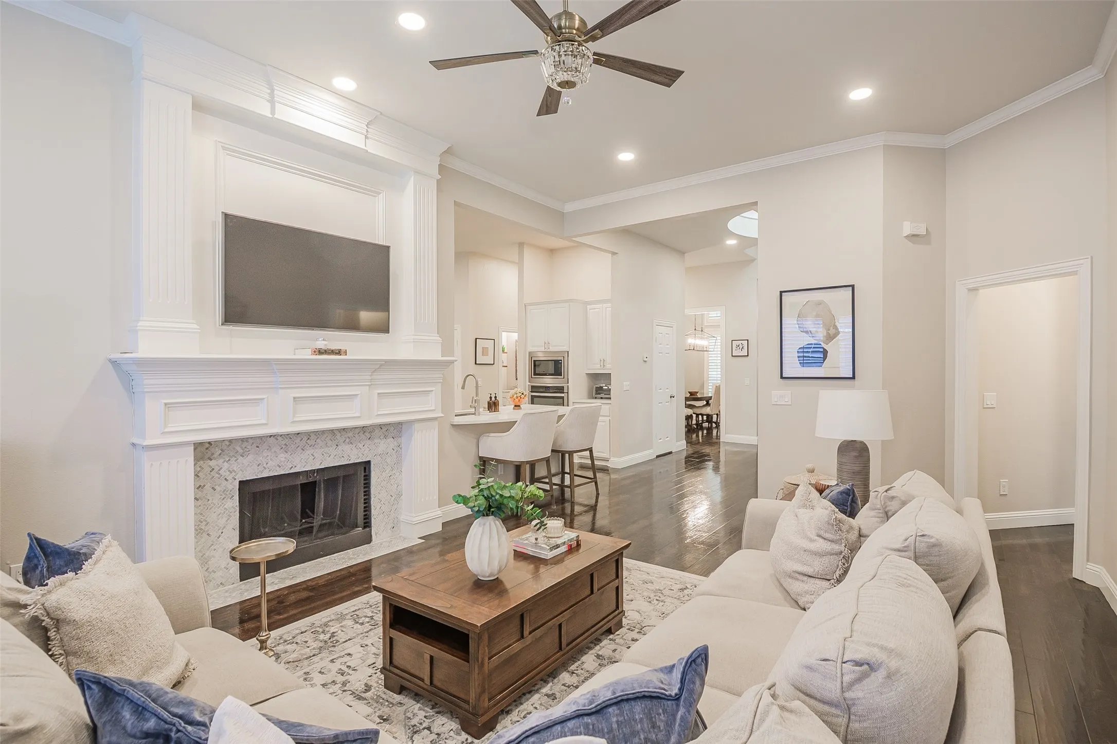 Fireplace with a decorative mantel, wood-finish flooring, recessed lighting, crown molding, and a ceiling fan with light fixture
