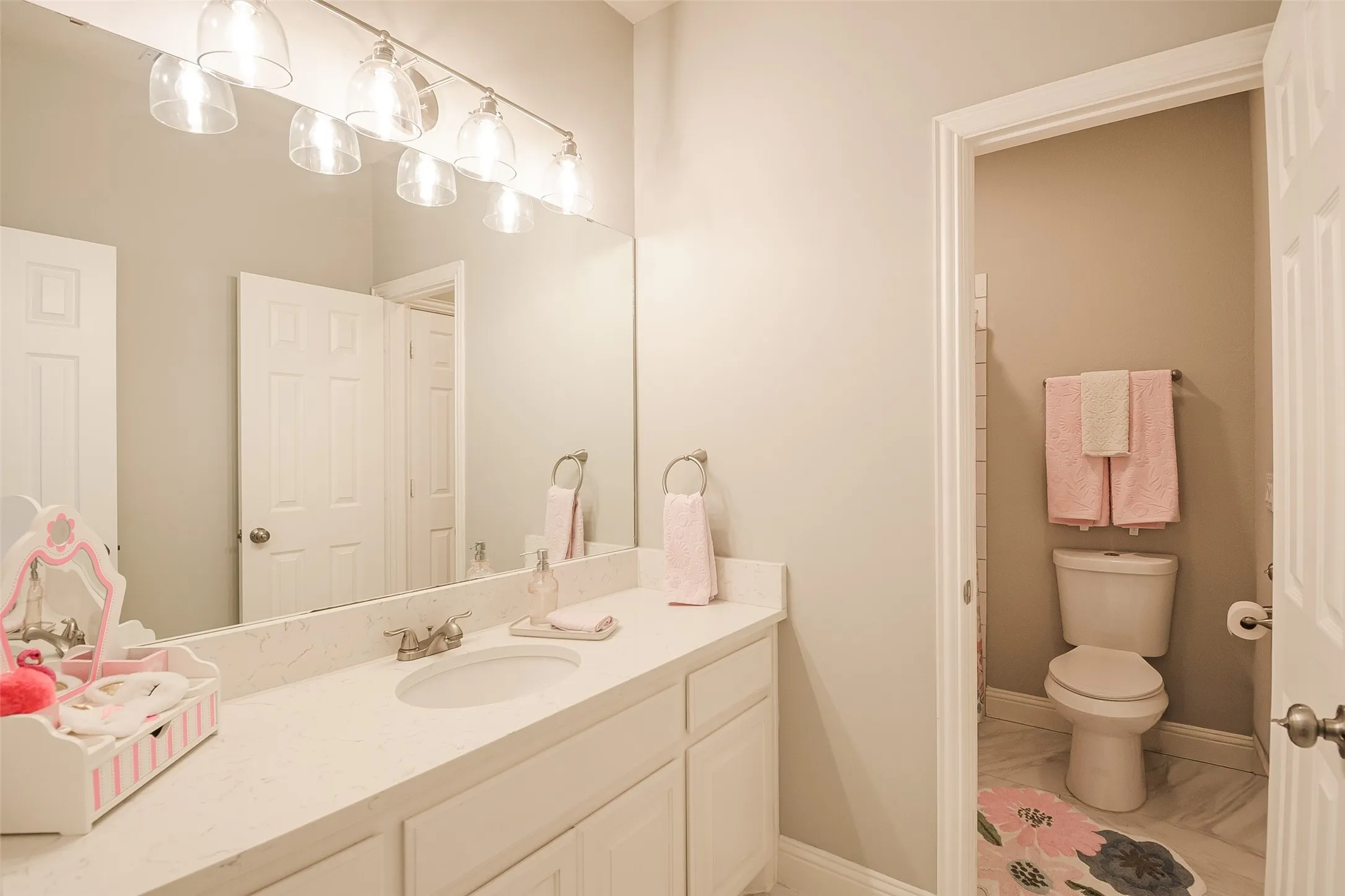 Spa-inspired bathroom featuring a generous dual-sink vanity with ample countertop storage, polished chrome fixtures, and a large framed mirror with integrated vanity lighting
