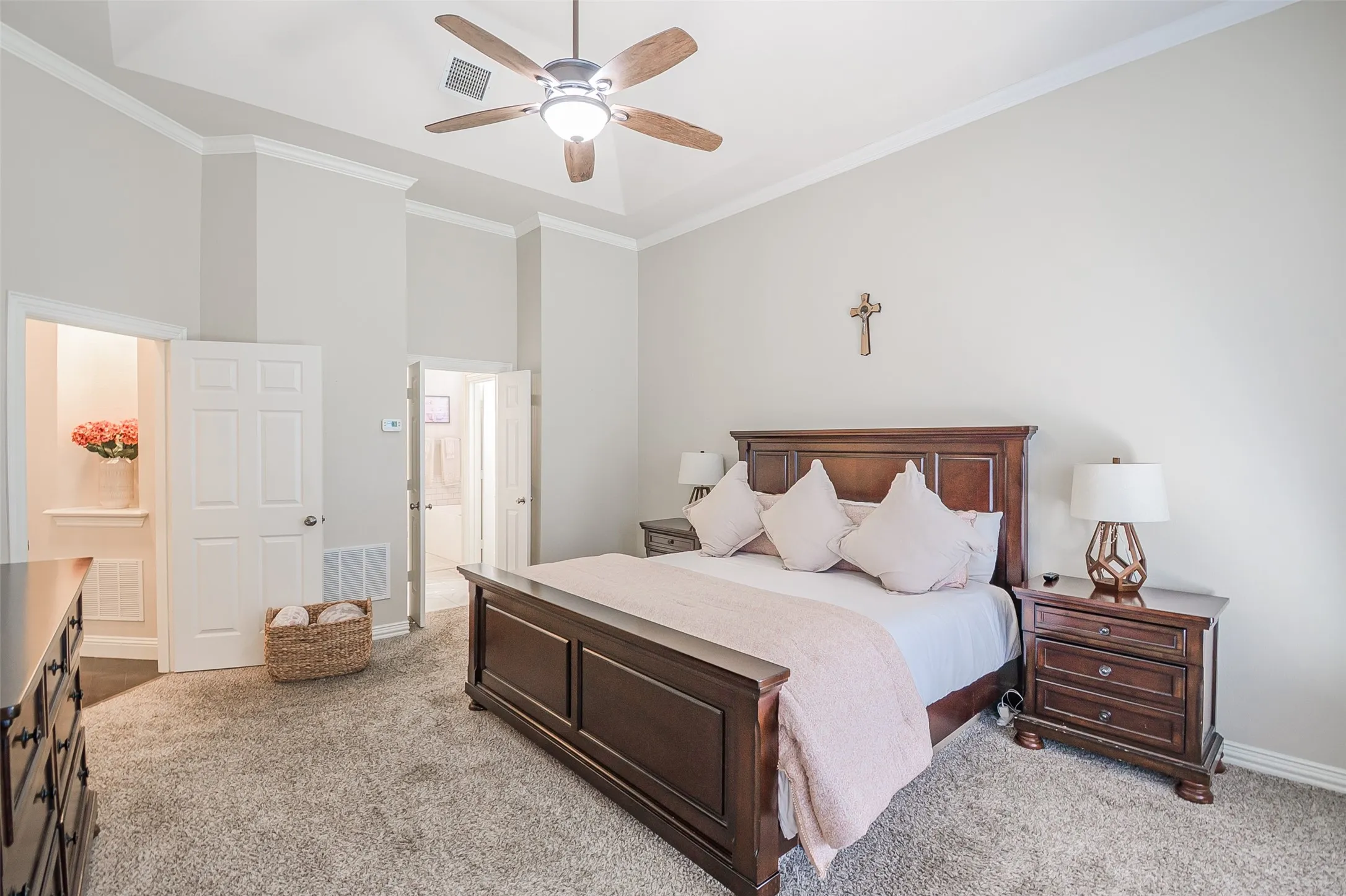 Vaulted ceiling with crown molding, ceiling fan with integrated lighting, carpeted flooring, and a six-panel door