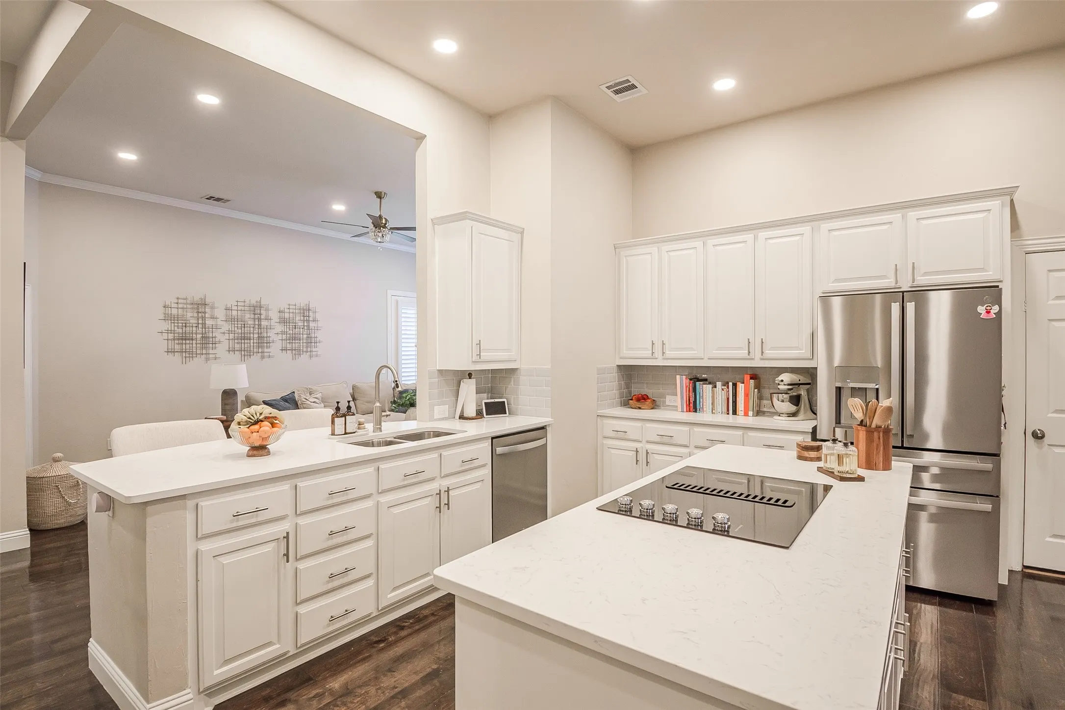 Kitchen featuring white cabinetry, stainless steel appliances, a center island with cooktop, quartz countertops, and dark wood-finish flooring