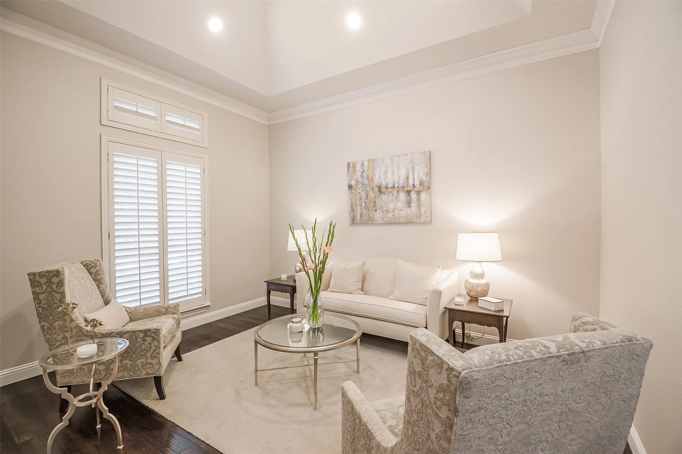 Wood-finish flooring, crown molding, plantation shutters, recessed lighting, and a tray ceiling