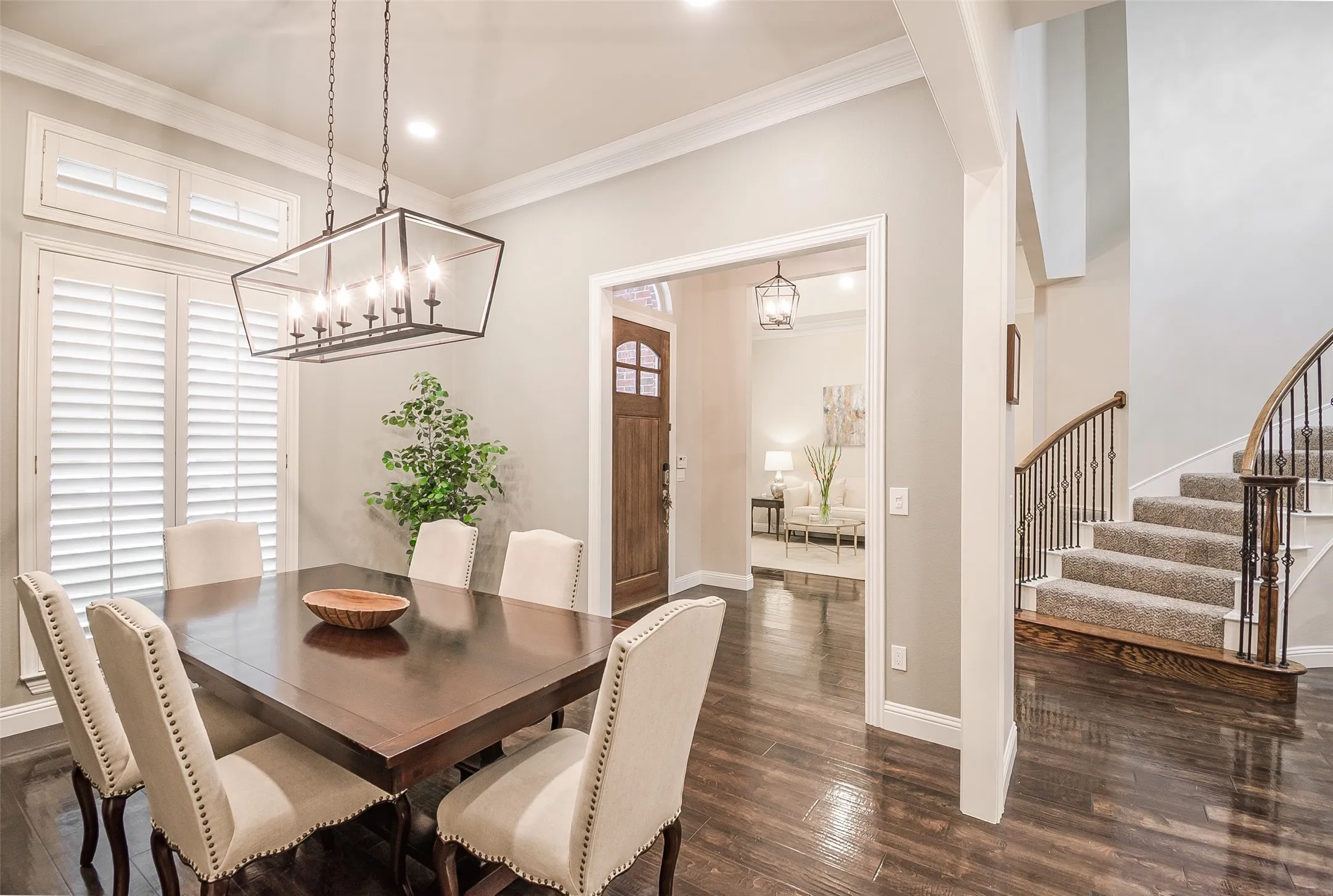 Dining area featuring wood-finish flooring, a linear chandelier, and window shutters