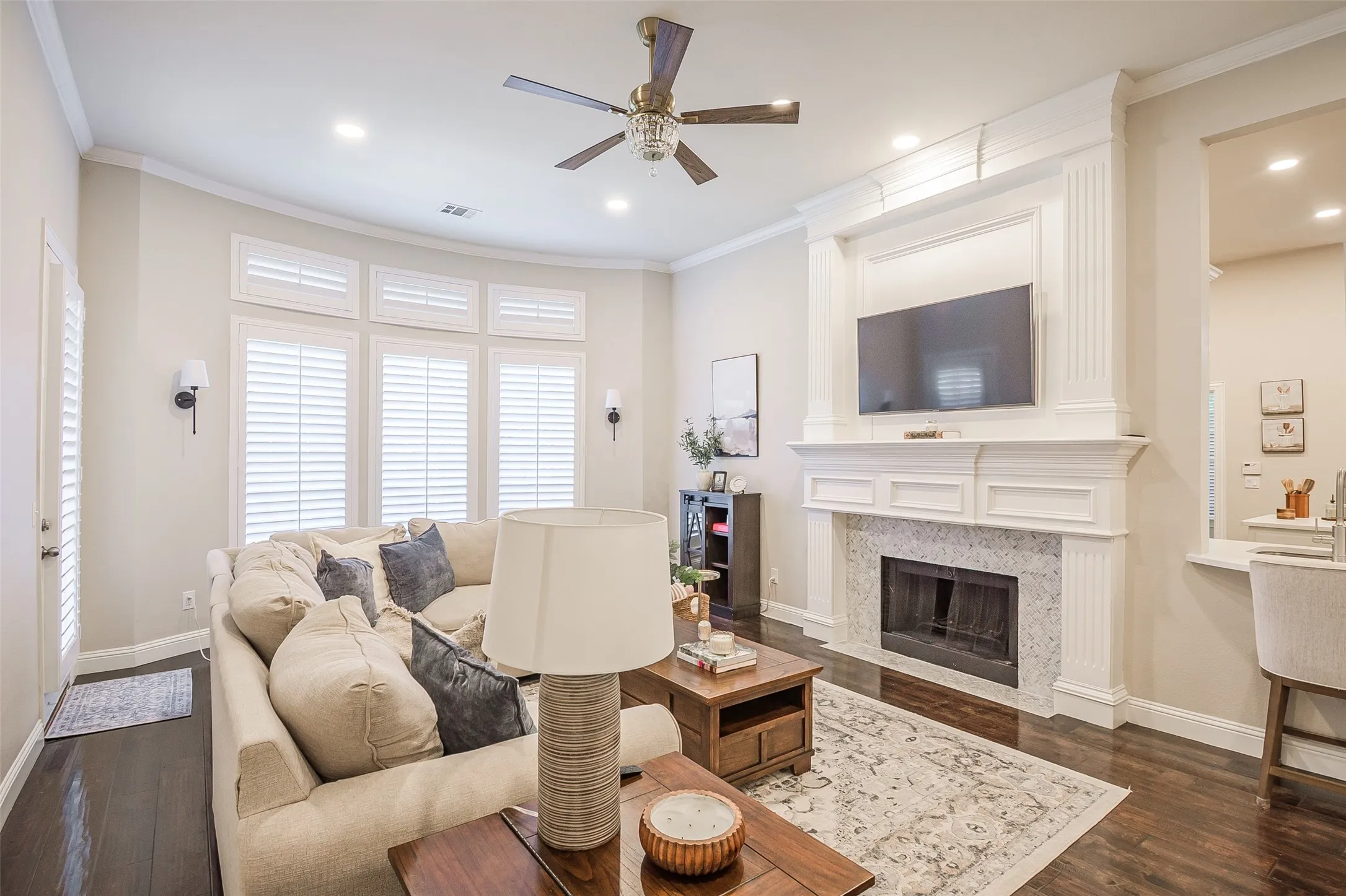 Living area featuring dark wood-finish flooring, a white mantel fireplace with a tile surround, recessed lighting, and a ceiling fan
