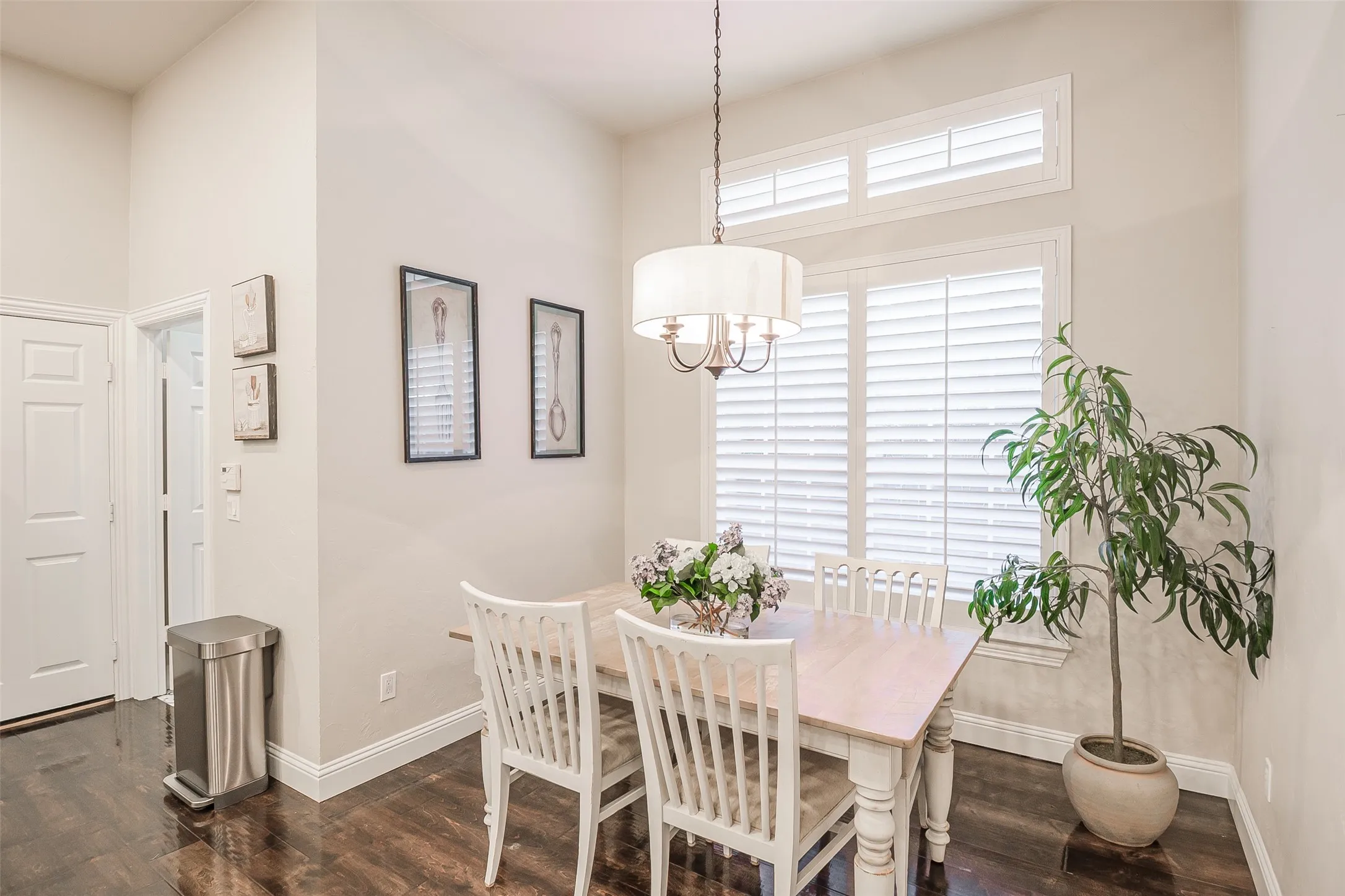 High ceilings with crown molding, wood-finish flooring, plantation shutters, and a drum-shade chandelier