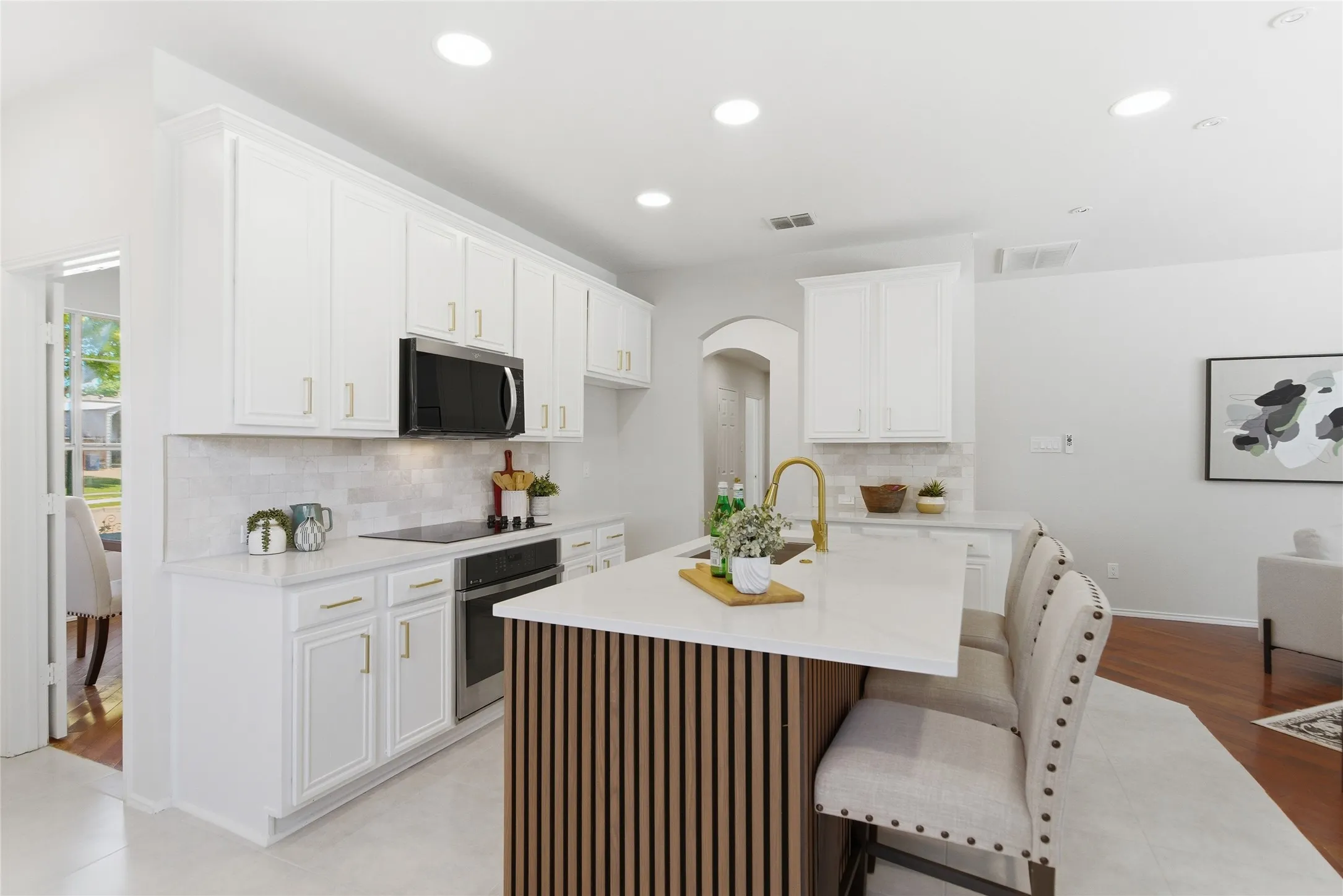 White shaker-style cabinetry with gold-finish hardware, stainless steel appliances, and a tile backsplash