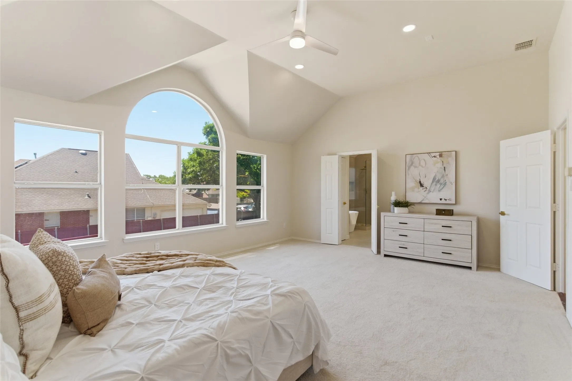 Vaulted ceilings with recessed lighting, large arched window, multiple windows, ceiling fan, and light-colored carpeting