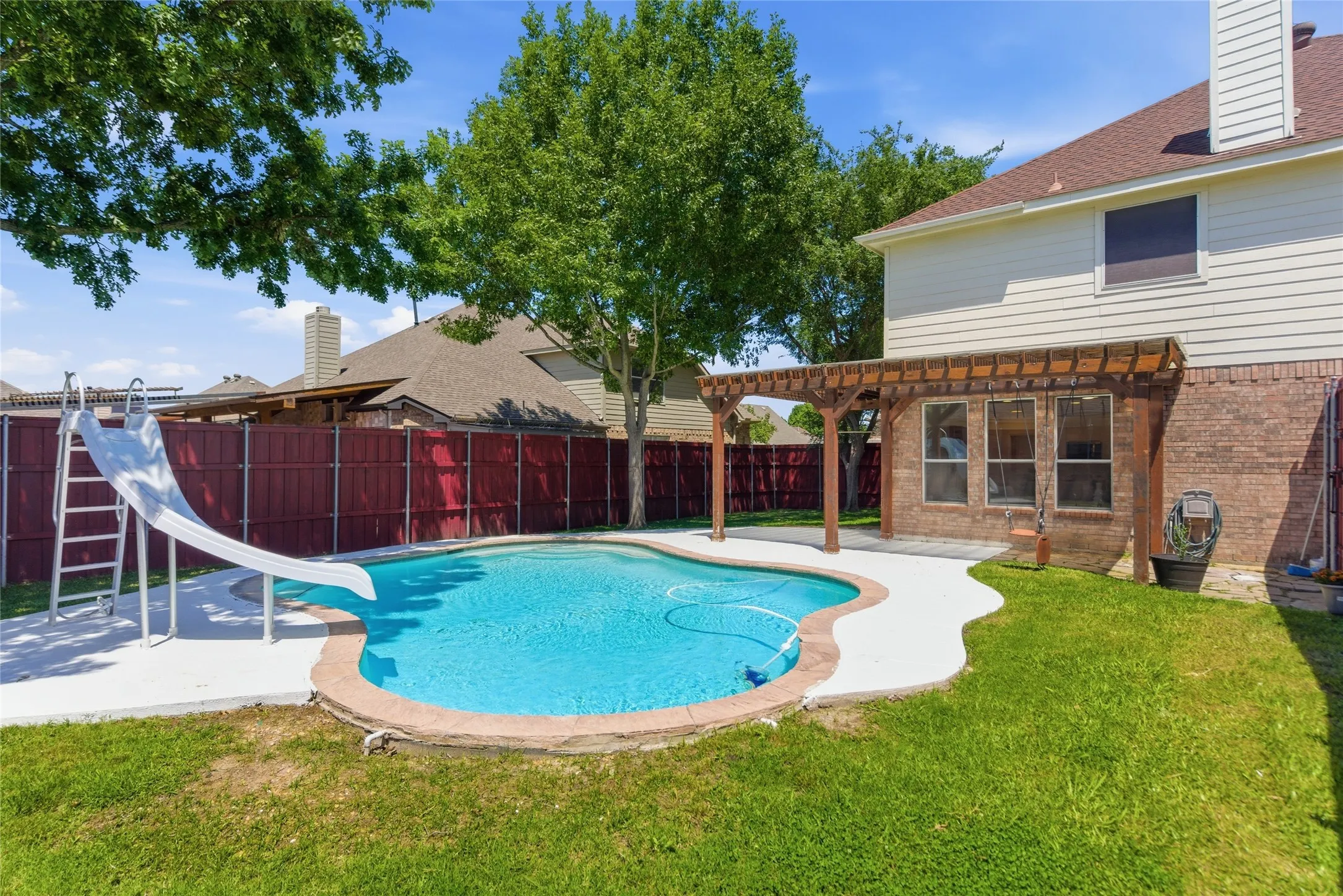 Private backyard featuring a swimming pool, concrete decking, and a wood pergola
