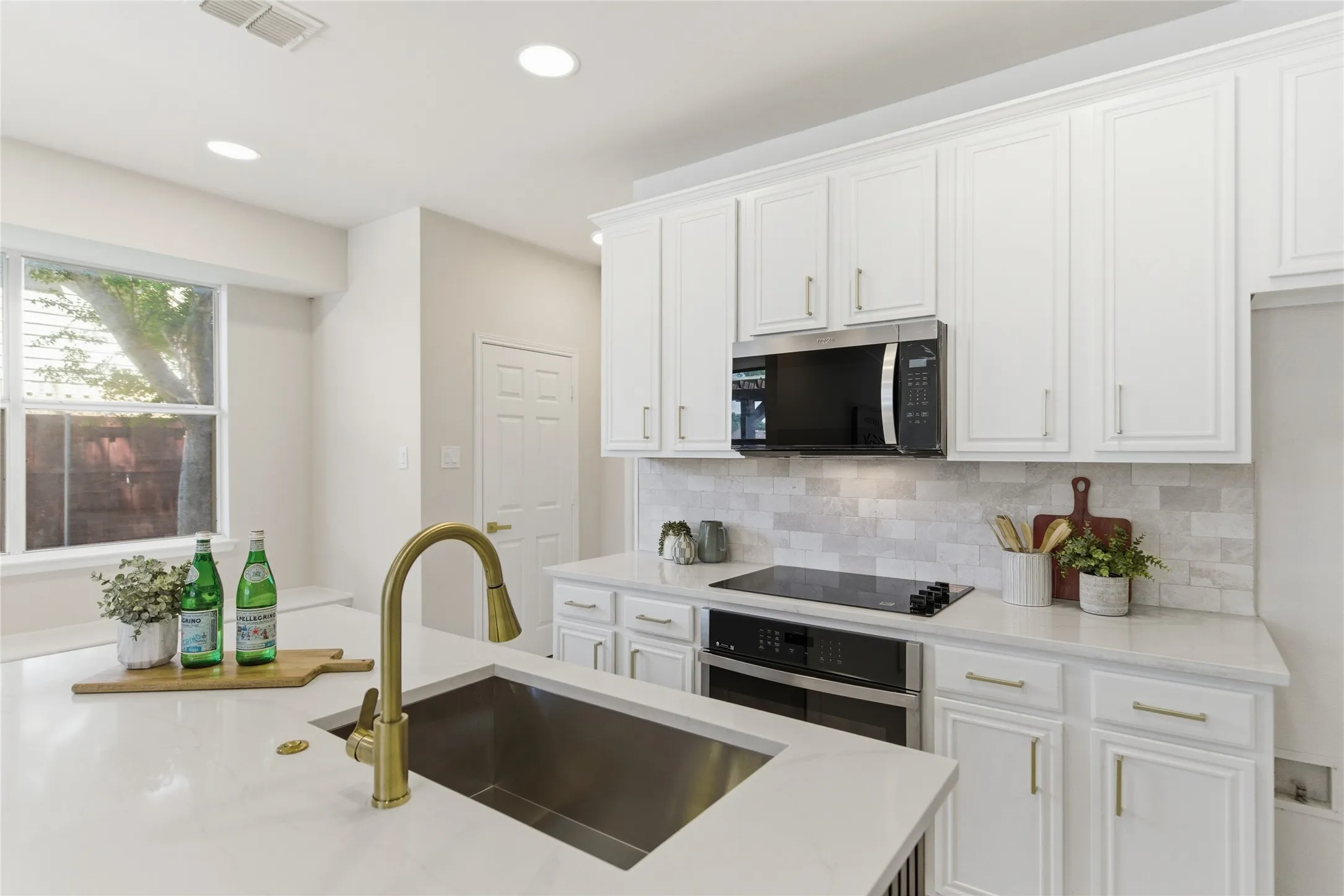 Kitchen featuring white cabinetry, a gold-tone gooseneck faucet, an undermount sink, recessed lighting, and a window
