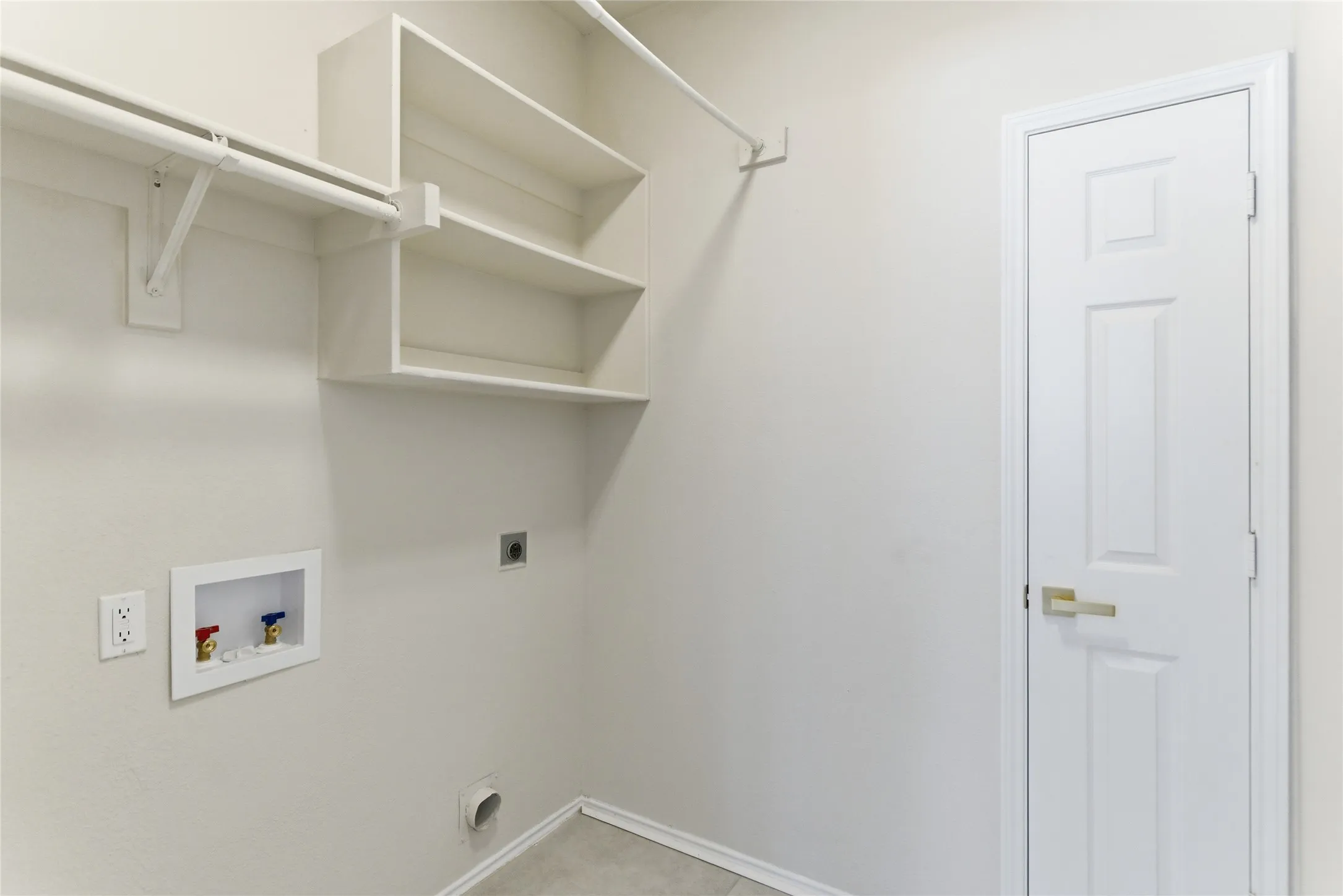 Laundry area featuring built-in shelving, a clothes hanging rod, and utility hookups