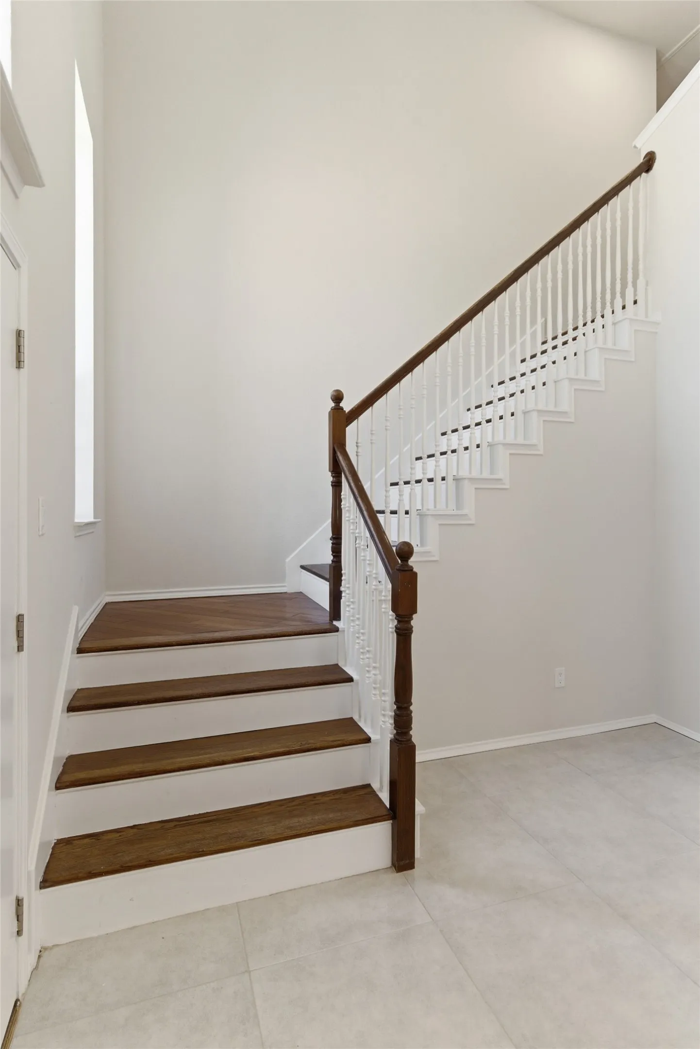 Staircase featuring wood-finish treads, white risers, and a classic wood balustrade