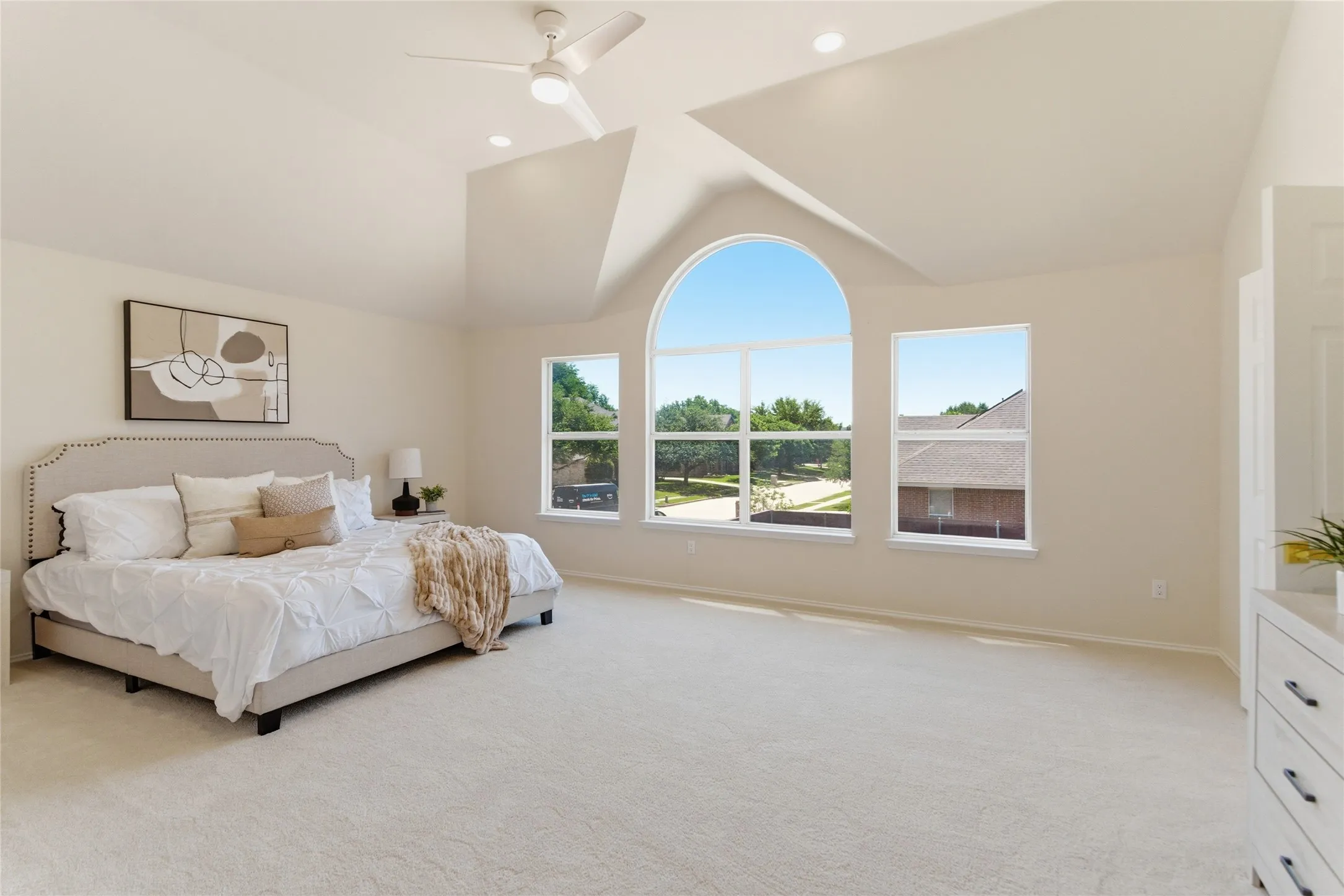Vaulted ceilings with recessed lighting, ceiling fan, arched window, and plush carpeting