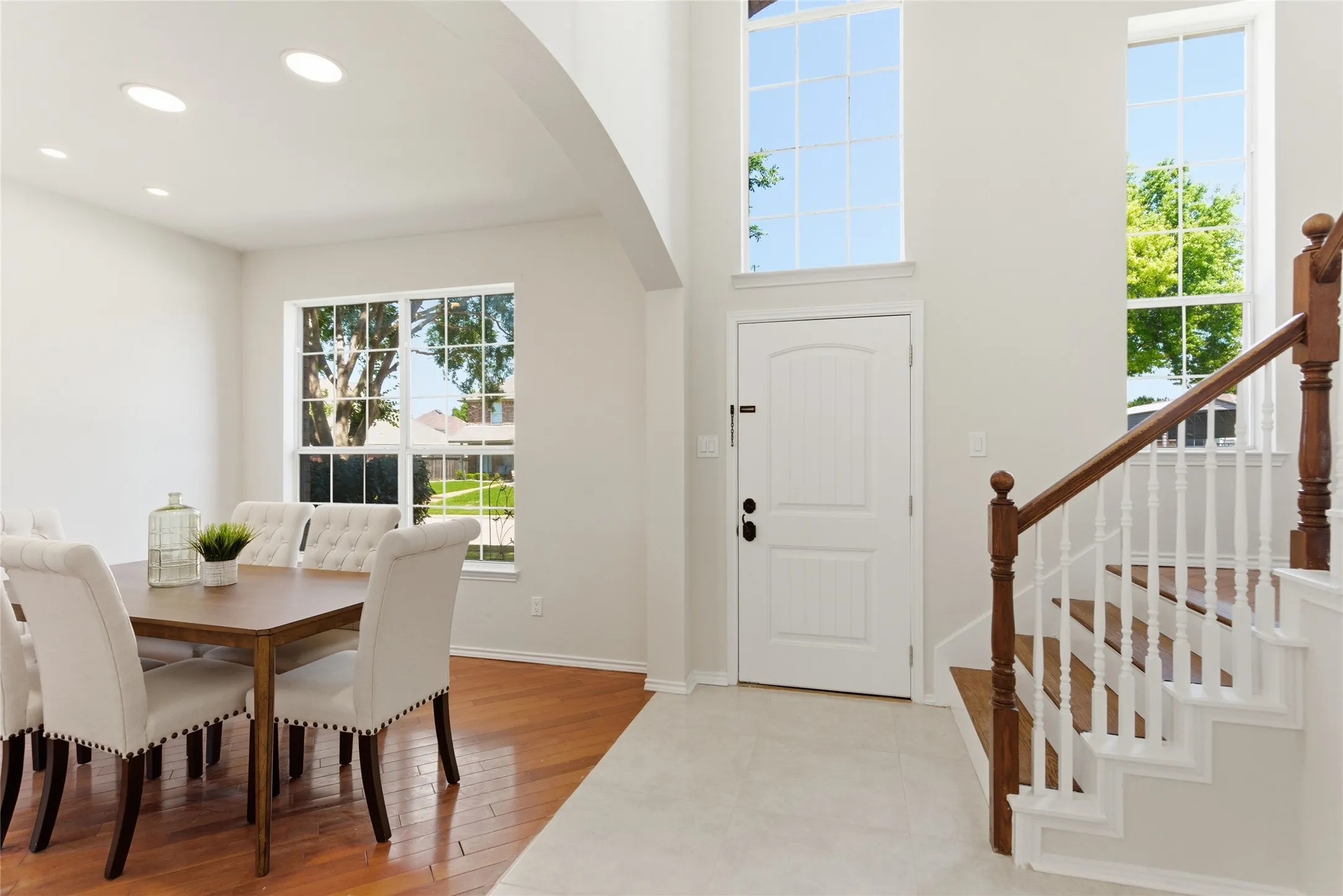 Two-story foyer with high ceilings, large windows, and a hardwood staircase with white risers and balusters
