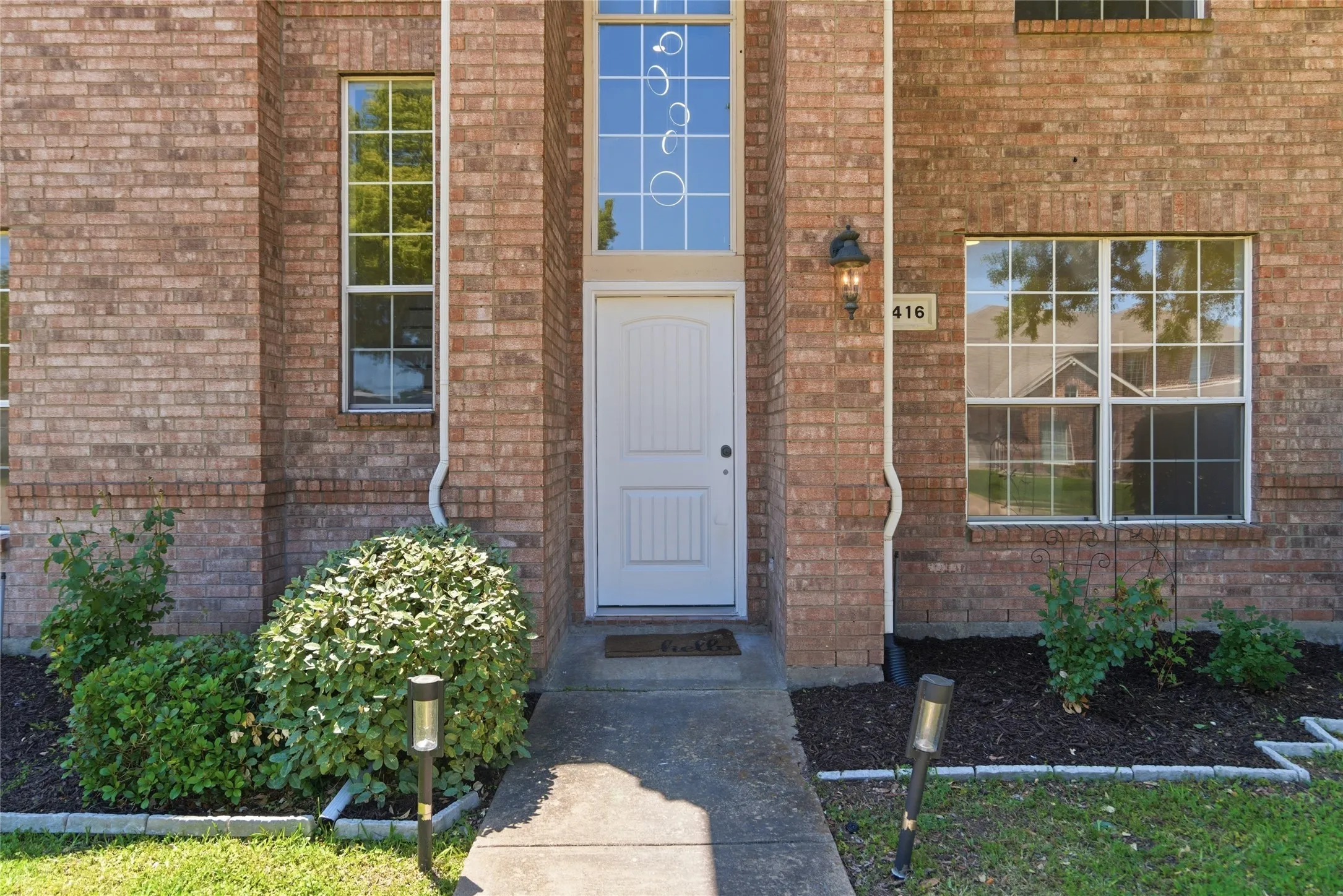 Brick exterior featuring a white entry door with an arched transom
