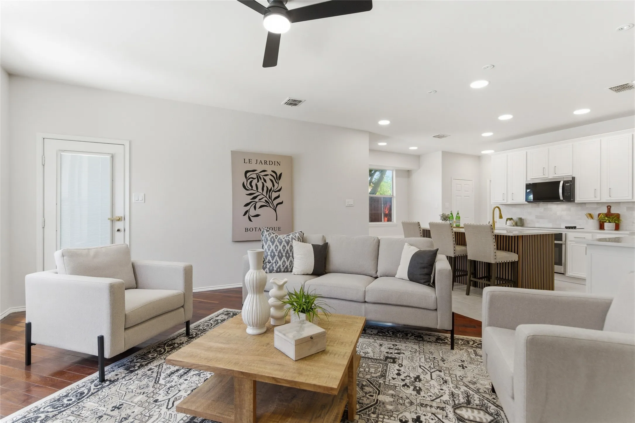 Open-concept living area featuring rich wood-finish flooring, recessed lighting, and a contemporary ceiling fan