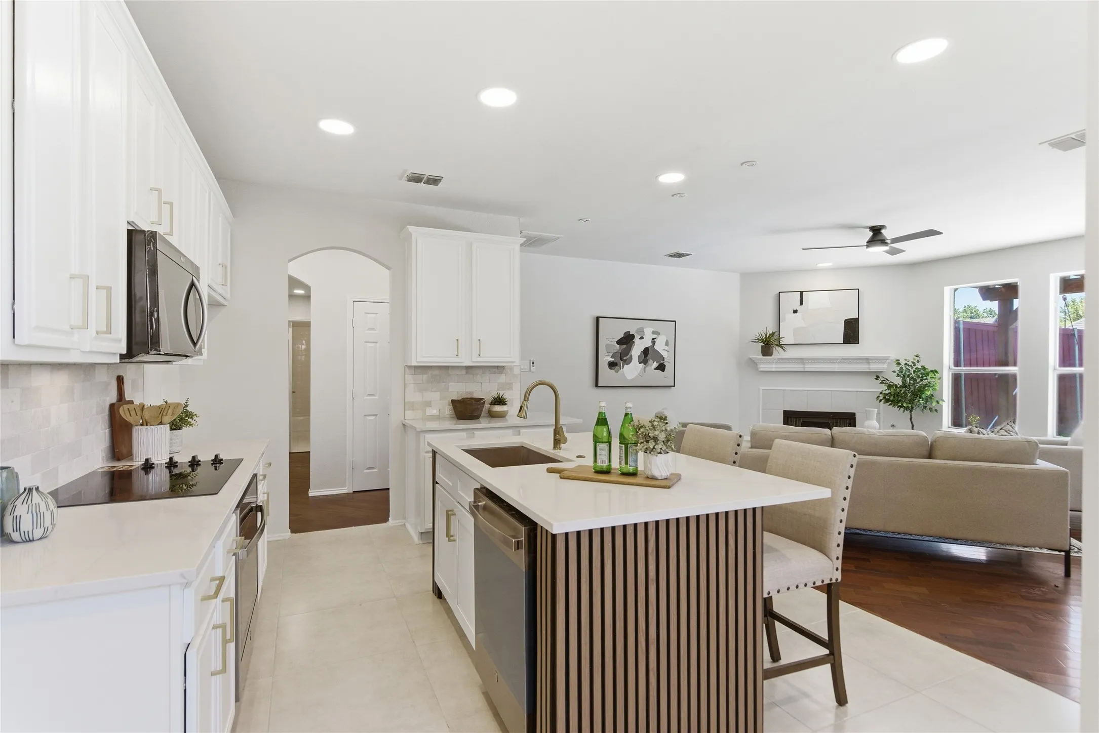 Kitchen featuring white cabinetry, a central island with slatted wood detailing, stainless steel appliances, and light-toned countertops