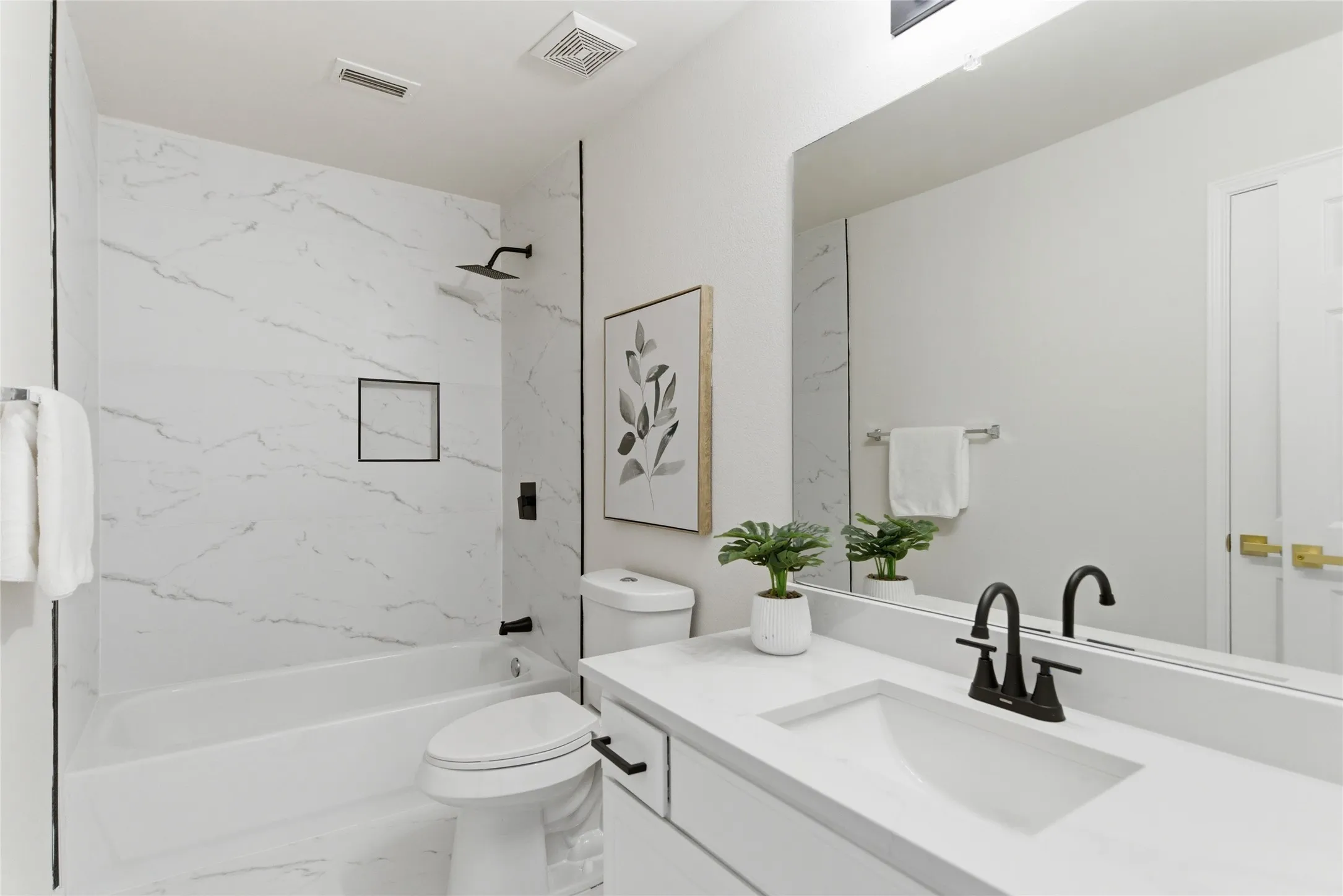 White floating vanity with integrated sink, black fixtures, and a large mirror