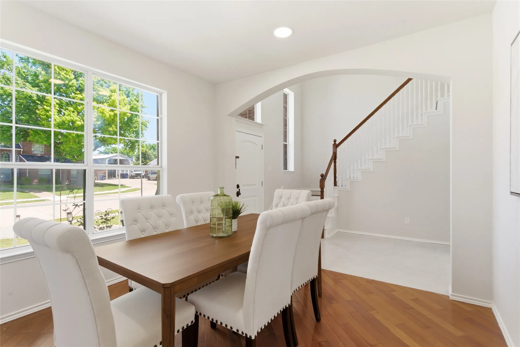 Hardwood flooring, divided light window, arched doorway, recessed lighting, and a staircase with a wood handrail