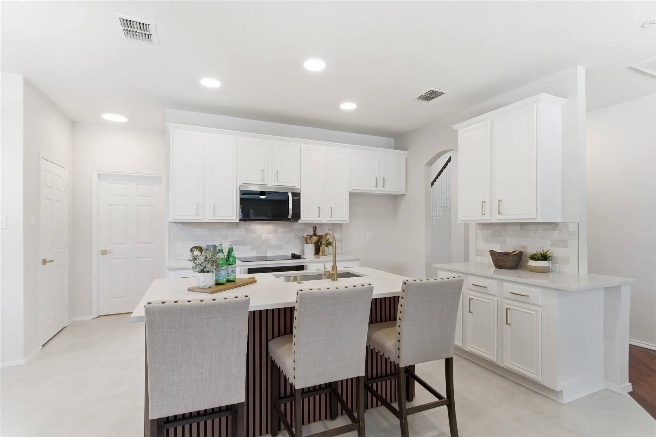 Kitchen featuring white cabinetry, a central island with a light-toned countertop, a tile backsplash, and recessed lighting
