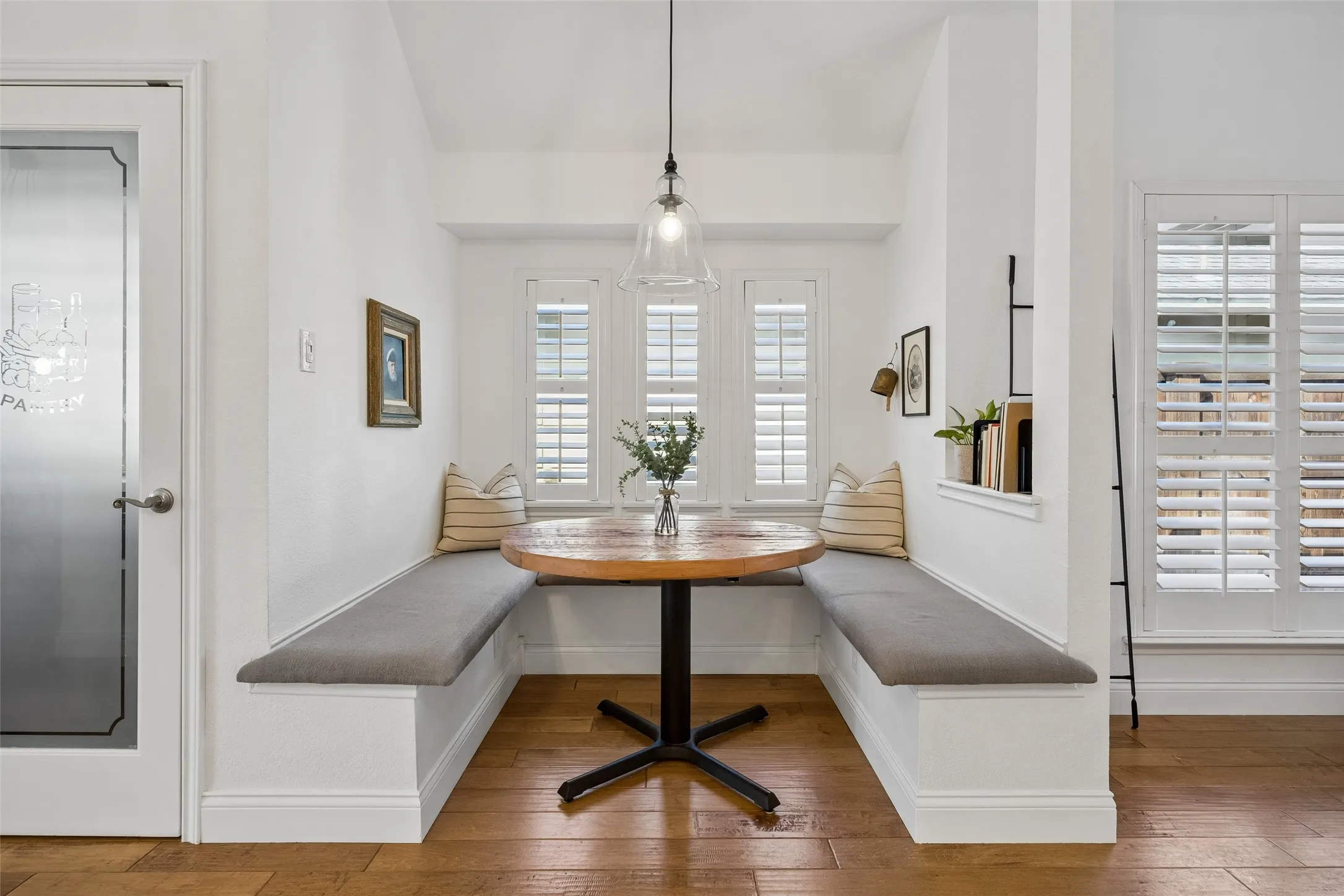 Cozy breakfast nook with built in seating, plantation shutters and a modern pendant light.