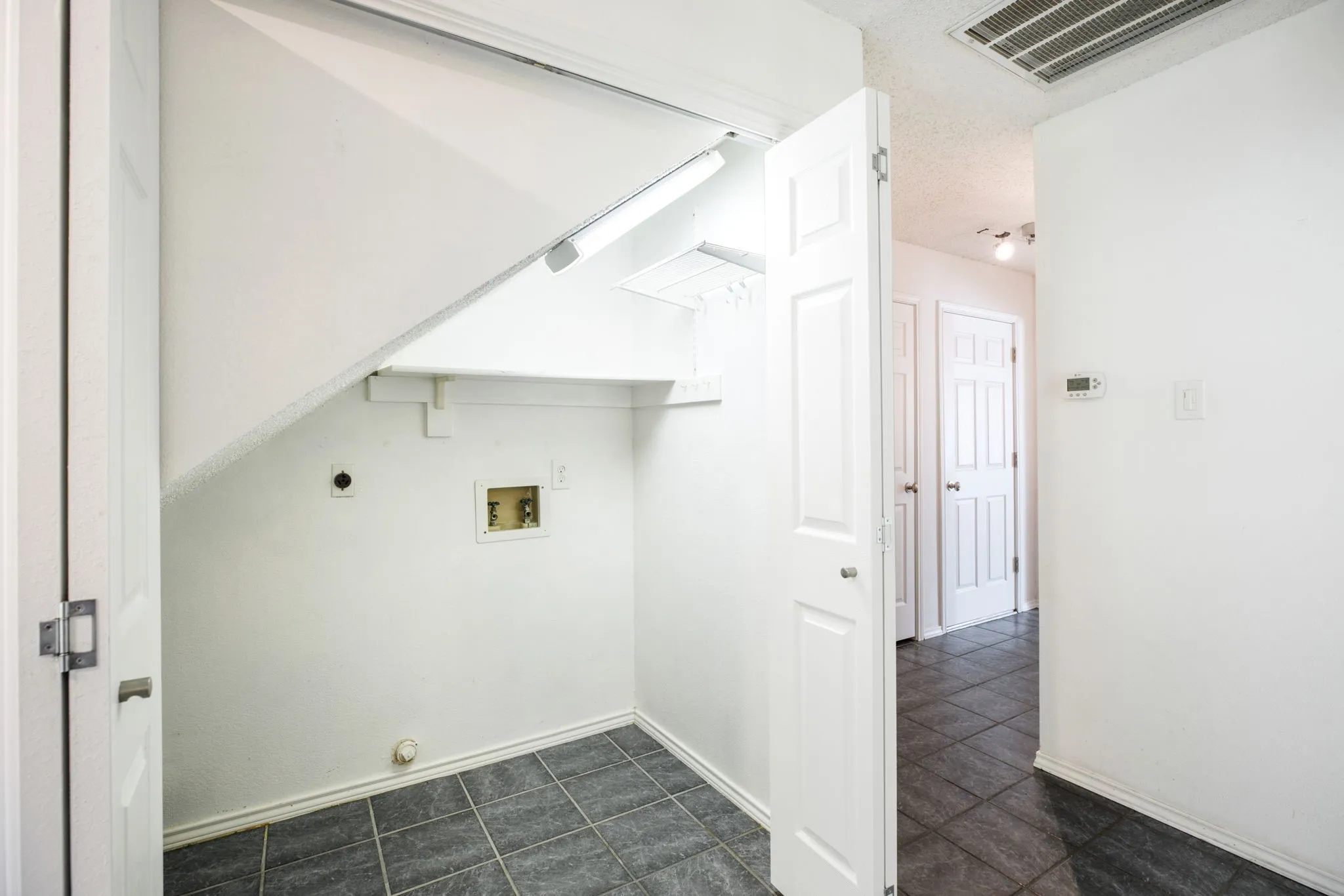 Laundry area featuring a utility hookup, tiled flooring, and a storage shelf