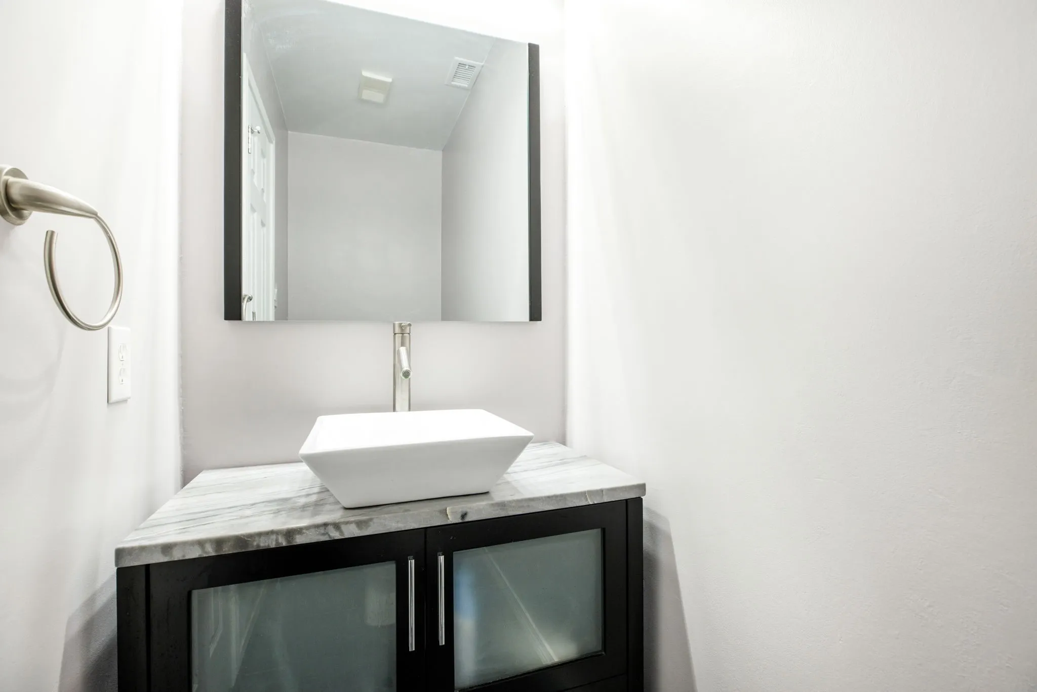 Floating vanity with a vessel sink, single-handle faucet, and stone countertop
