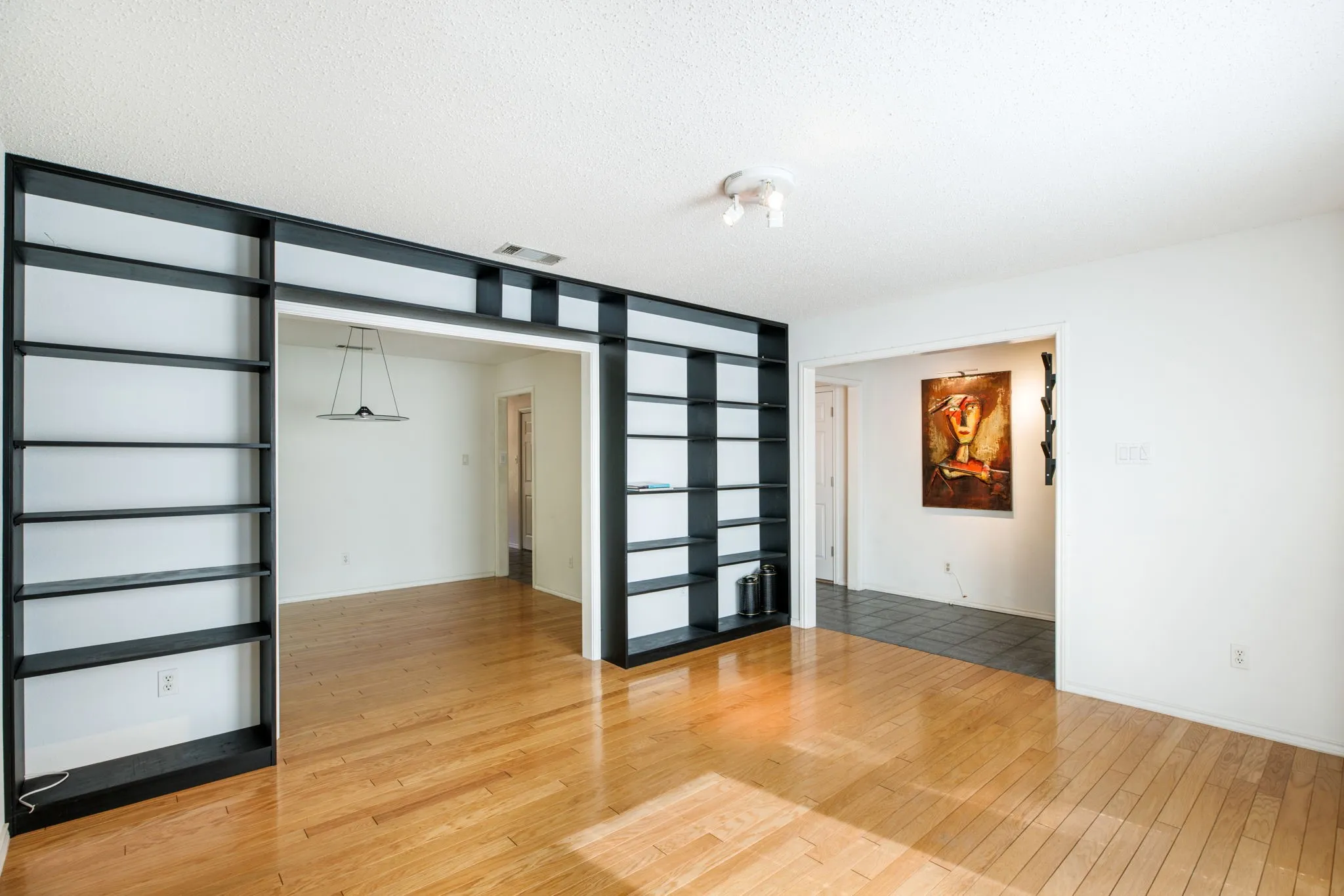 Hardwood flooring, recessed lighting, and built-in shelving with an open archway