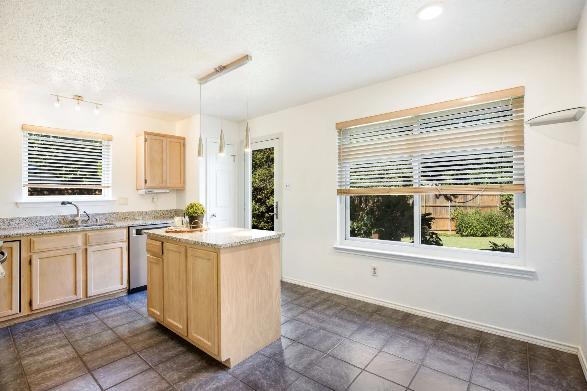 Kitchen featuring wood cabinetry, a center island with countertop, tile flooring, and track lighting