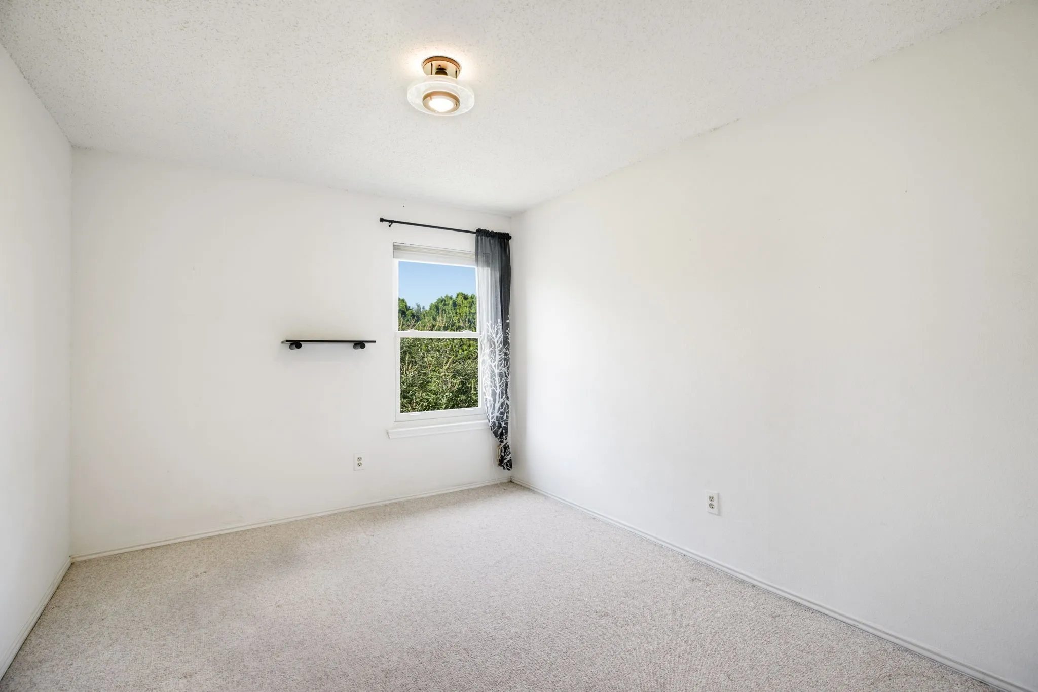 Window with outdoor scenery, recessed lighting, wall-mounted shelf, light-toned carpeting