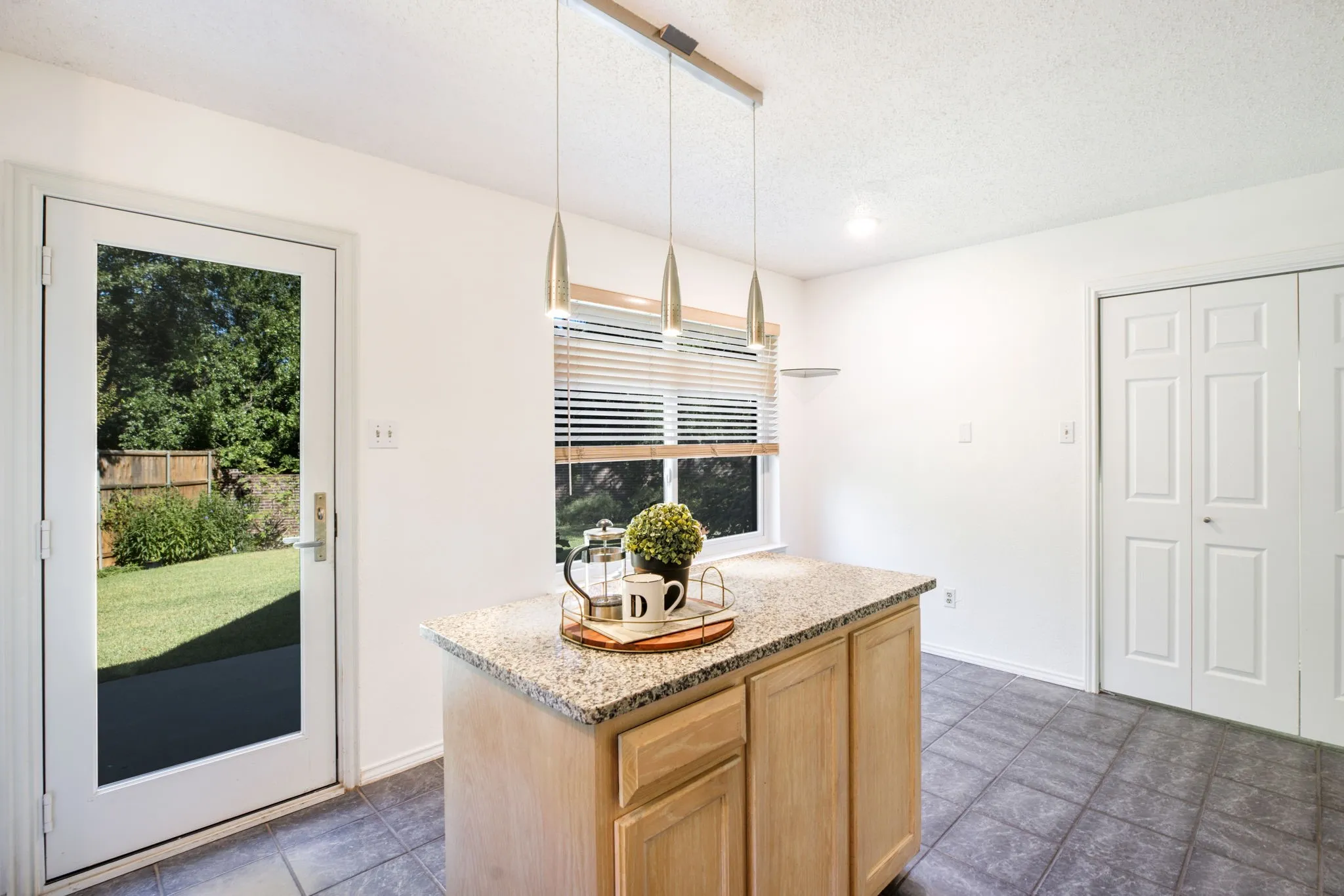Kitchen island with a granite-style countertop, pendant lighting, and wood-finish cabinetry