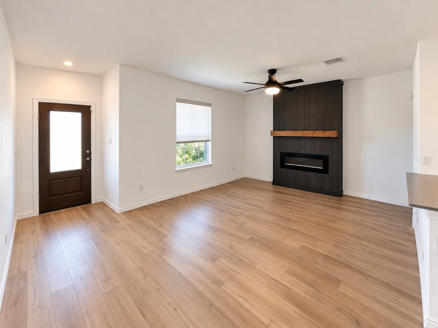 Recessed lighting, wood-finish flooring, dark wood-paneled fireplace surround with wood mantel, electric fireplace, and ceiling fan with integrated lighting