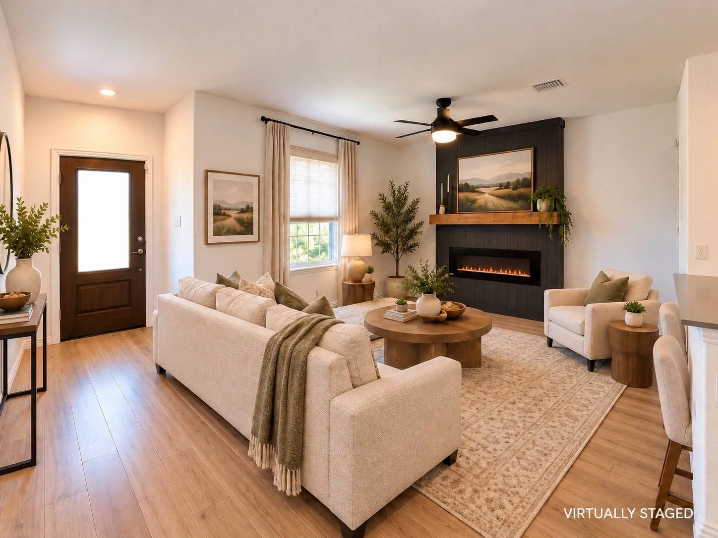 Living area featuring wood-finish flooring, an electric fireplace with a wood mantel, and a ceiling fan.