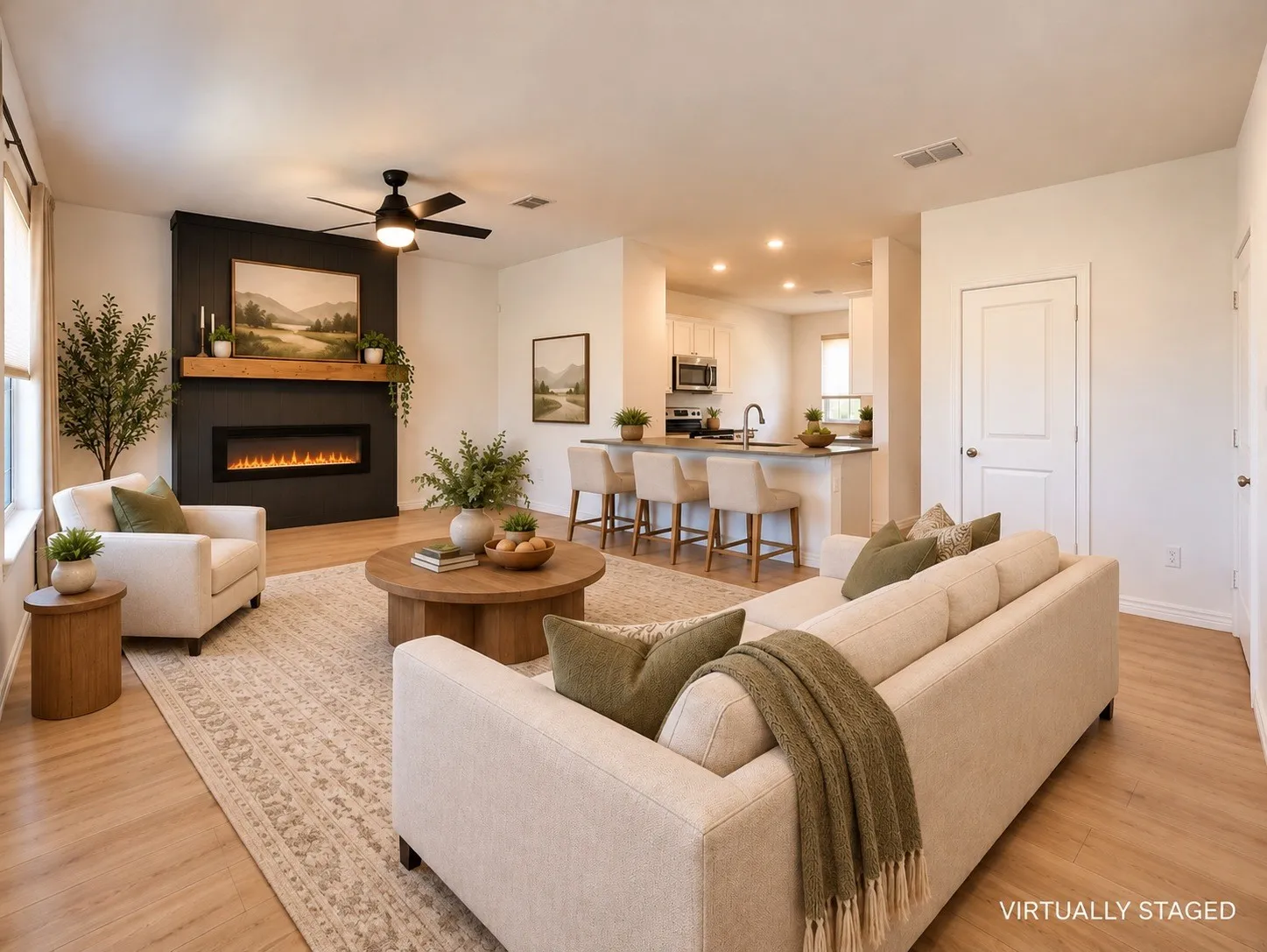 Open-concept living area with wood-finish flooring, a contemporary ceiling fan, and a built-in electric fireplace featuring a wood mantel