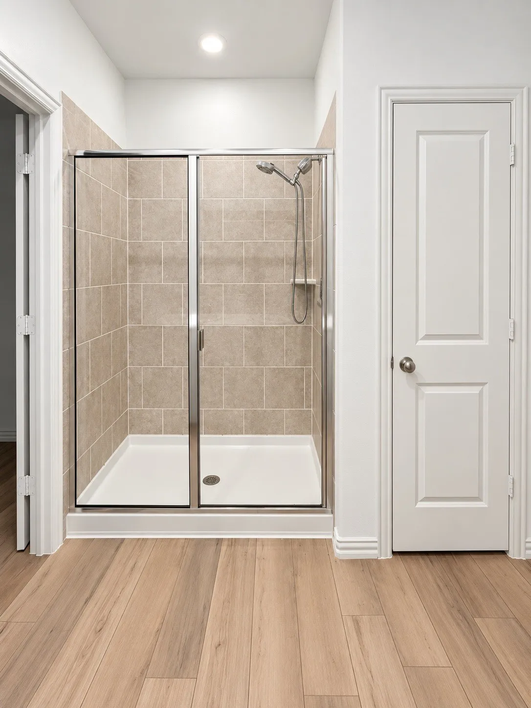 Walk-in shower with clear glass enclosure and tile surround