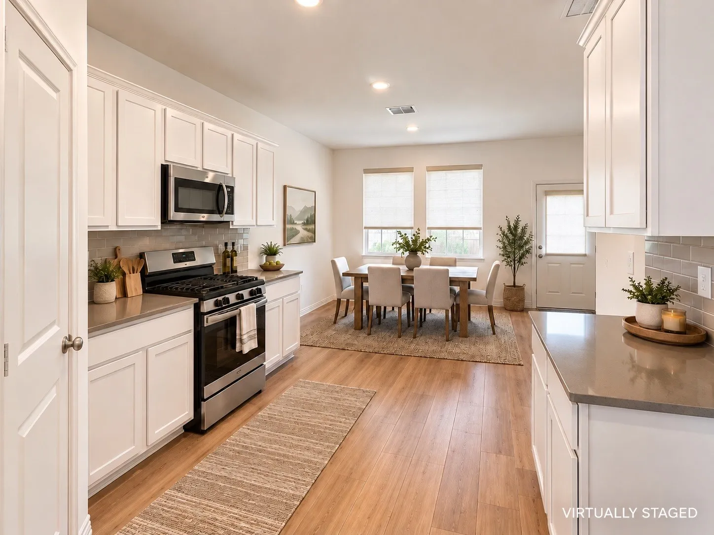 White shaker cabinetry, stainless steel appliances, wood-finish flooring, and light countertops