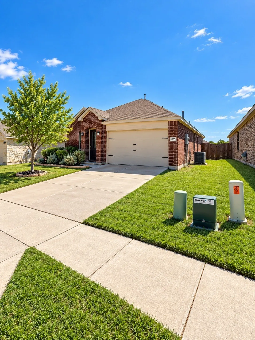 Brick exterior, attached garage, concrete driveway, concrete walkway, mature landscaping