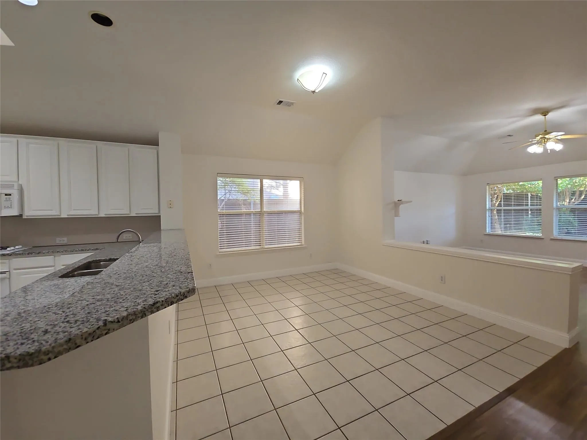 White cabinetry, granite countertops, tile flooring, and vaulted ceilings