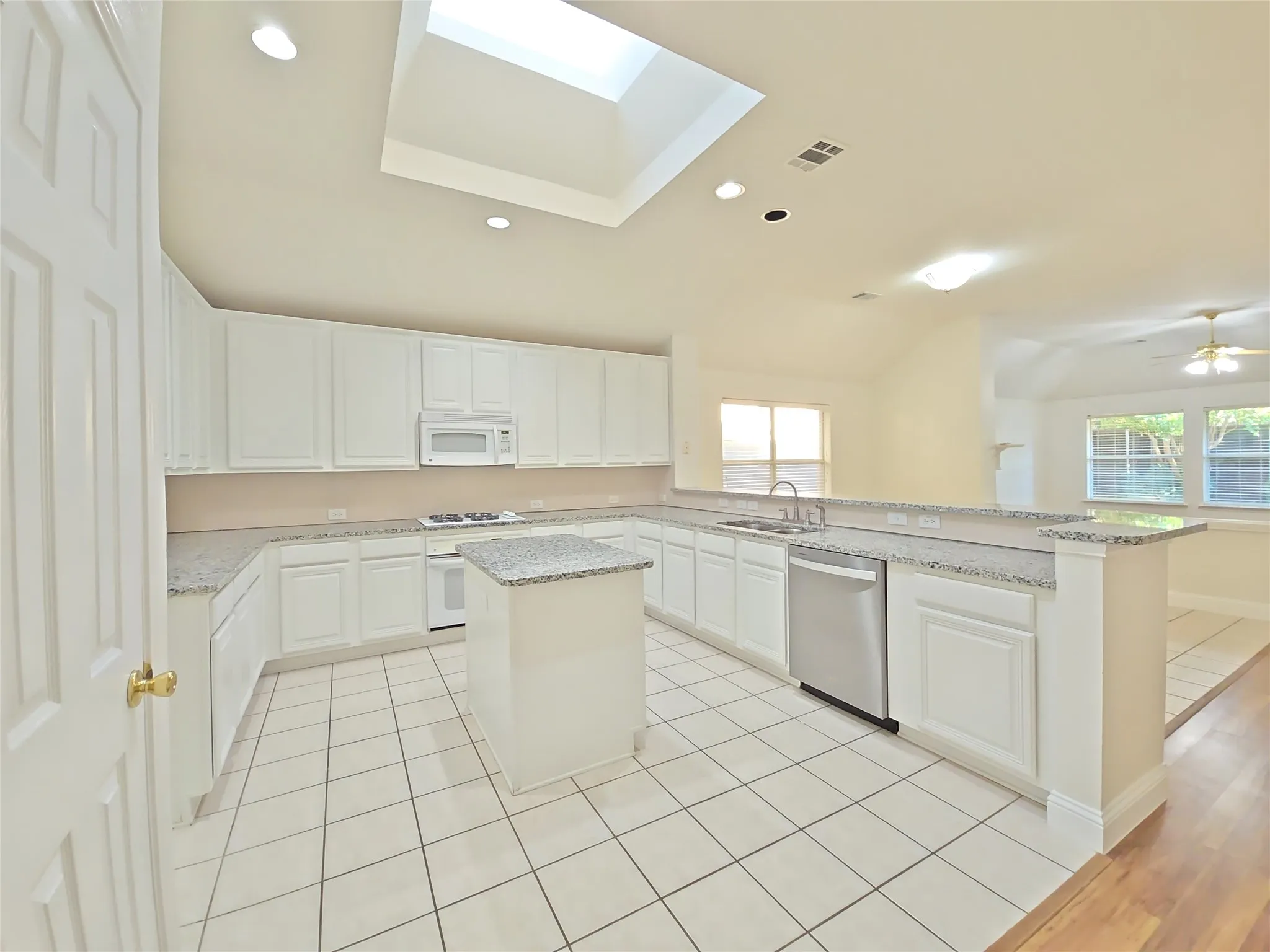Kitchen featuring white cabinetry, light-toned countertops, a central island, and stainless steel appliances