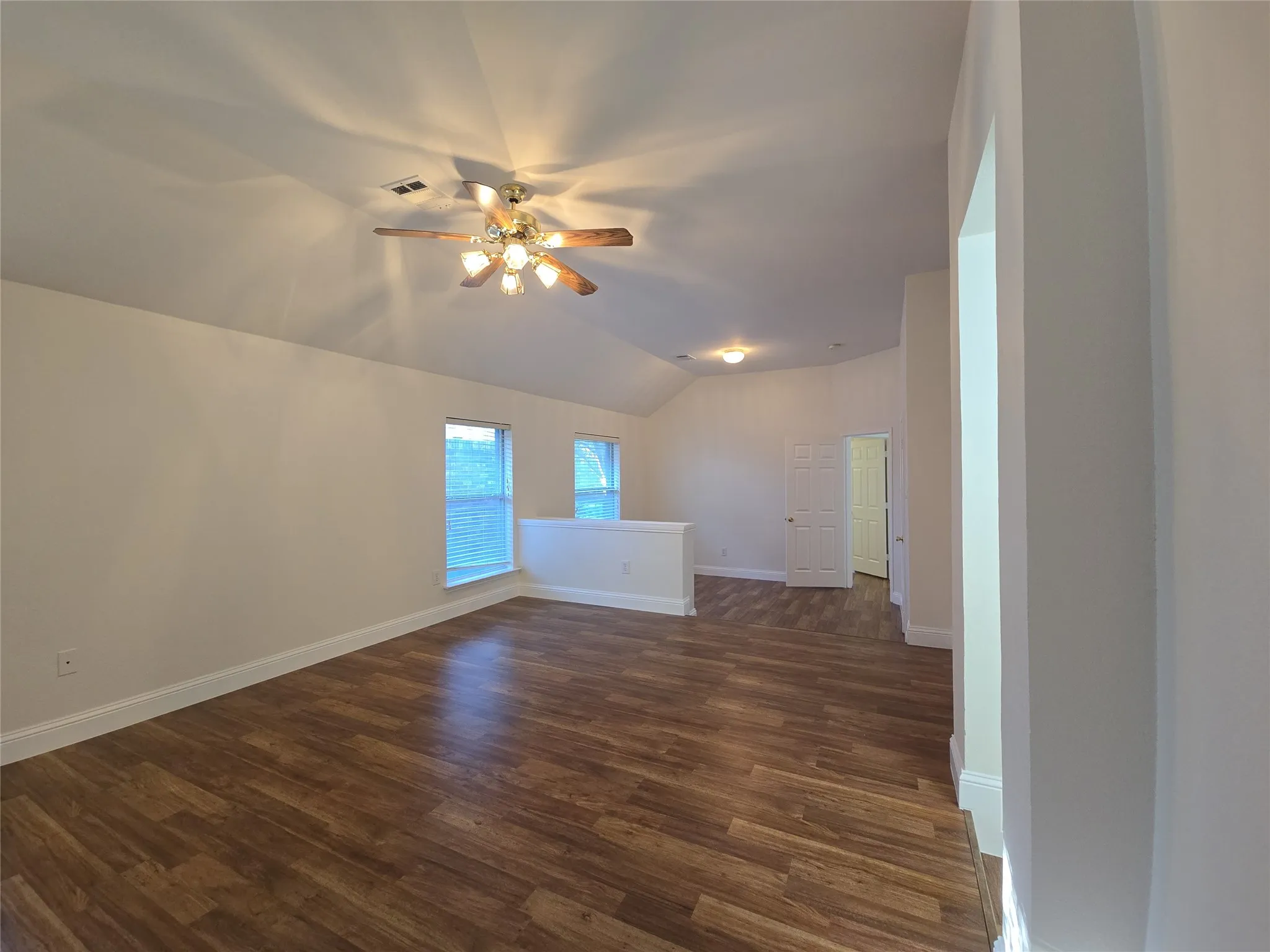 Vaulted ceiling with a ceiling fan, wood-finish flooring, multiple windows, and recessed lighting