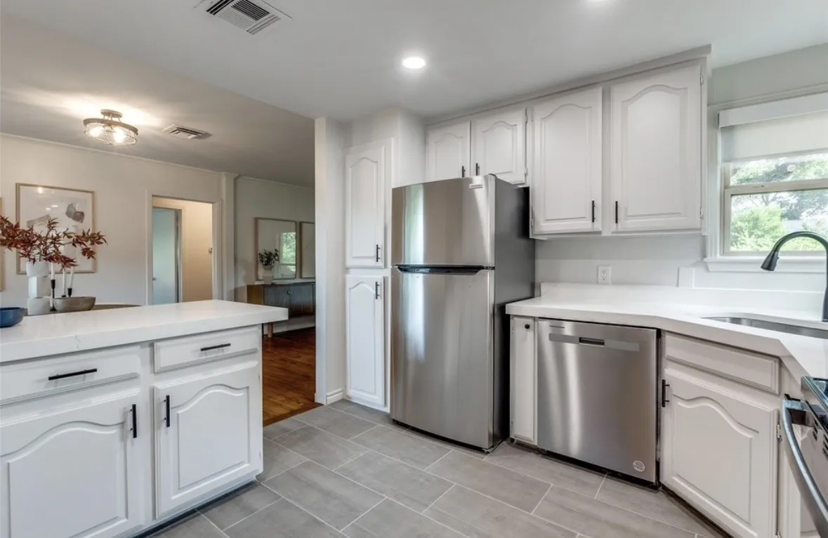 White cabinetry with black hardware, stainless steel appliances, quartz countertops, tile flooring, and recessed lighting