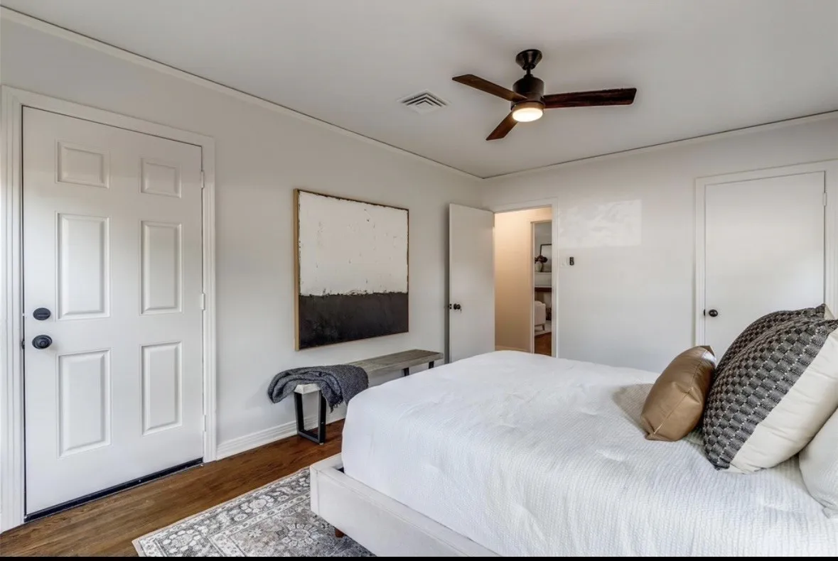 Wood-finish flooring, white paneled doors, ceiling fan with integrated lighting, and neutral wall tones