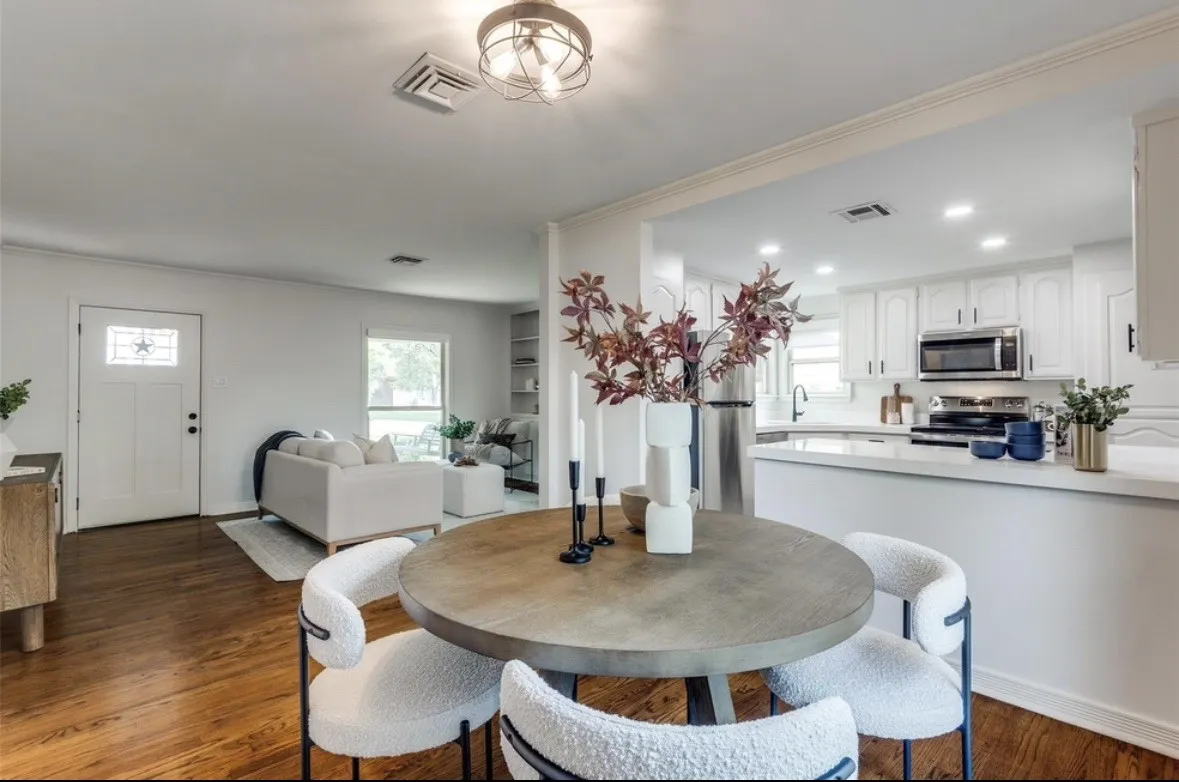 Hardwood-style flooring throughout, white kitchen cabinetry, stainless steel appliances, recessed lighting, and a white front entry door with decorative glass