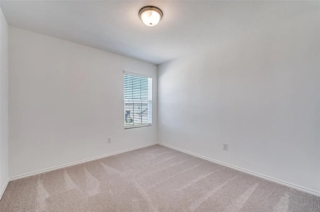 Neutral paint palette, single window with blinds, carpeted flooring, and ceiling-mounted light fixture