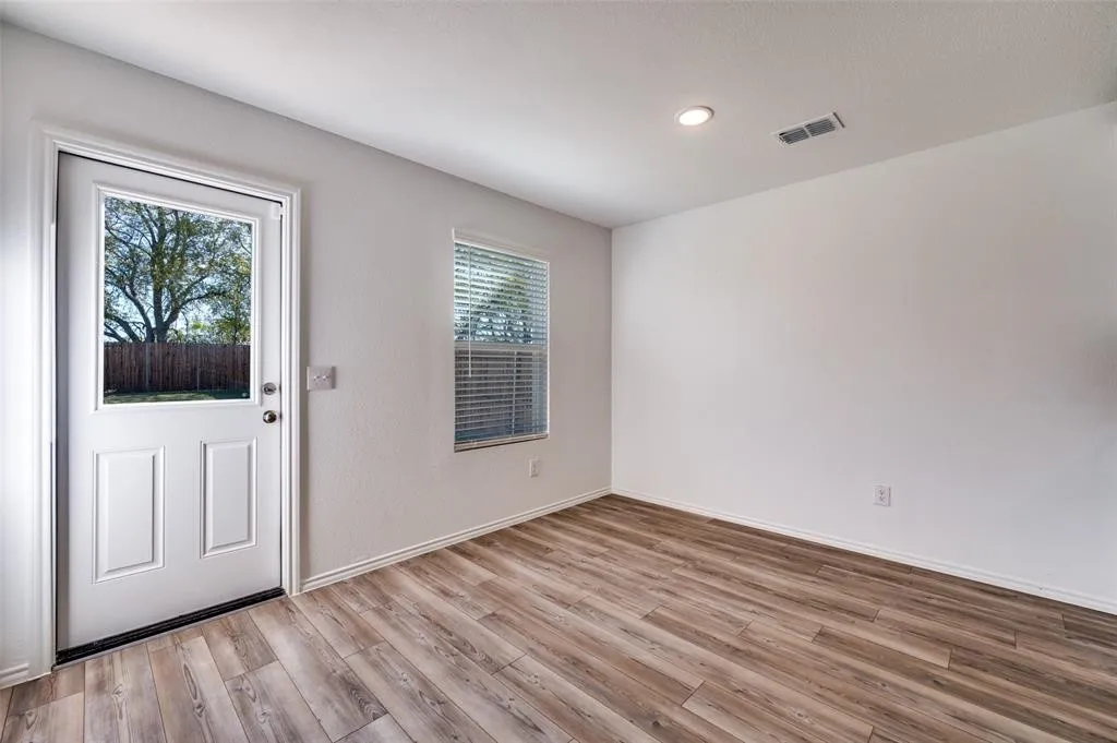 Wood-finish flooring, white walls, recessed lighting, and a window with blinds provide a bright and neutral interior