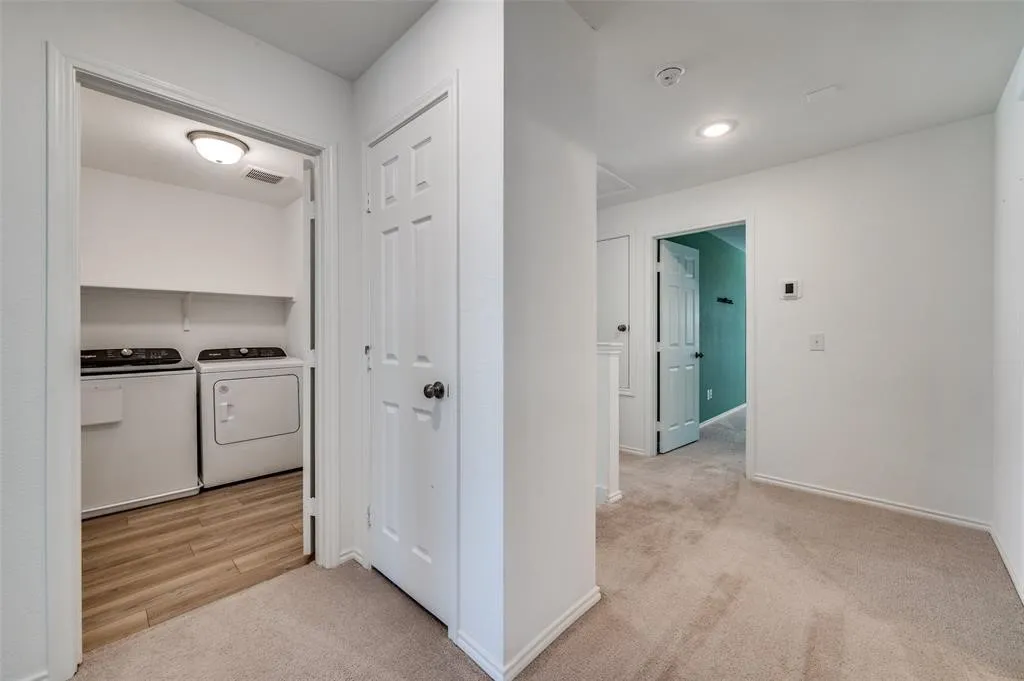 Laundry space with wood-finish flooring, two upper shelves, and an overhead light fixture