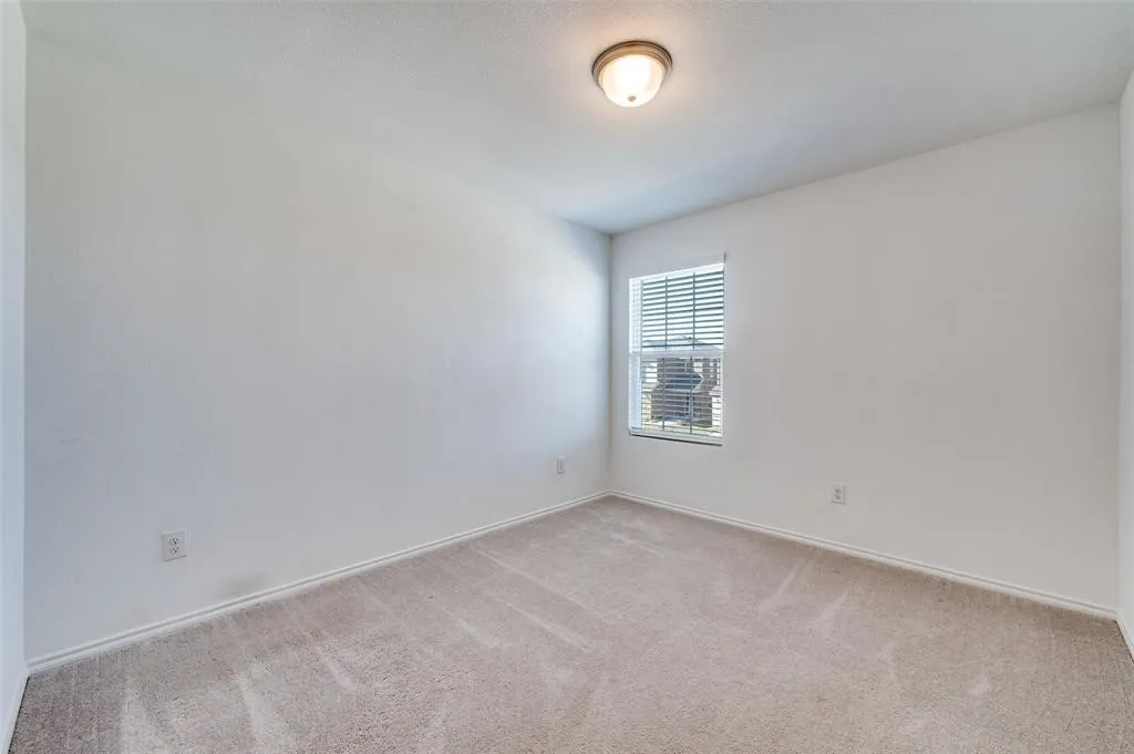 Carpeted room featuring a single window with blinds and a ceiling-mounted light fixture