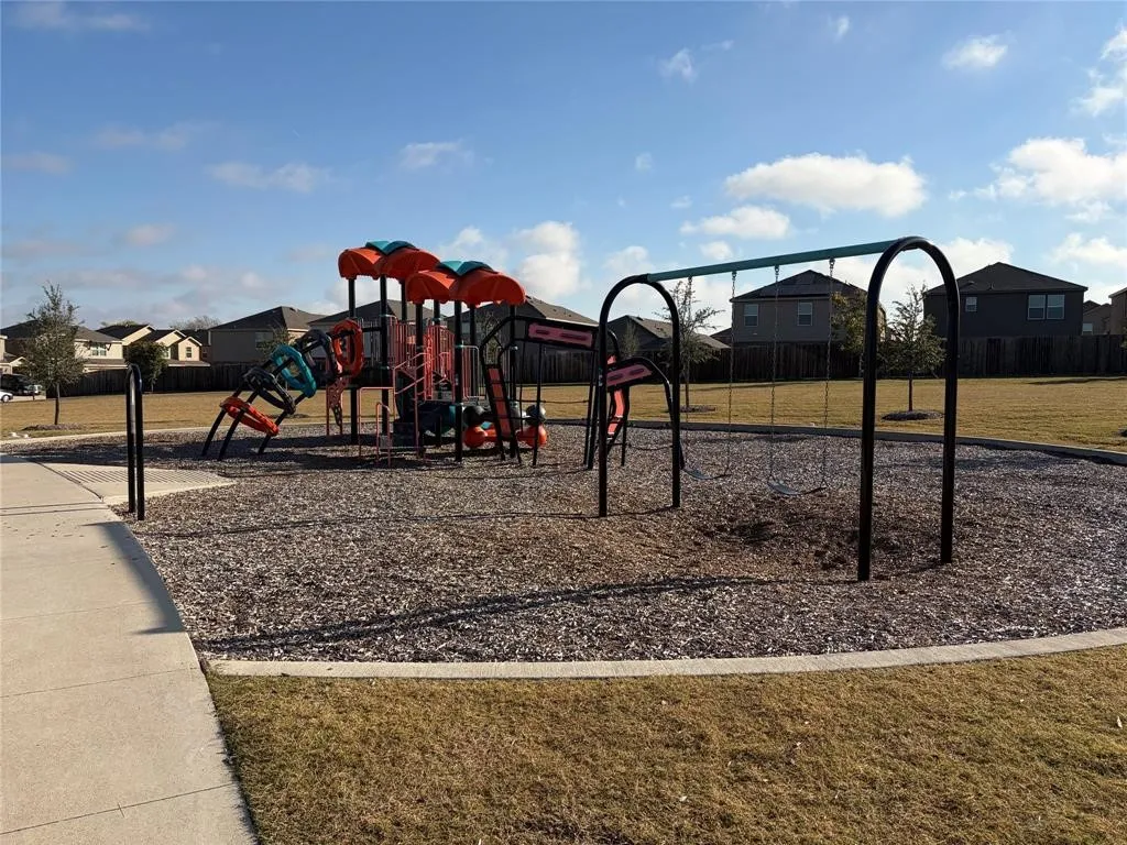 Community playground featuring a multi-level play structure, swing set, and wood chip surfacing