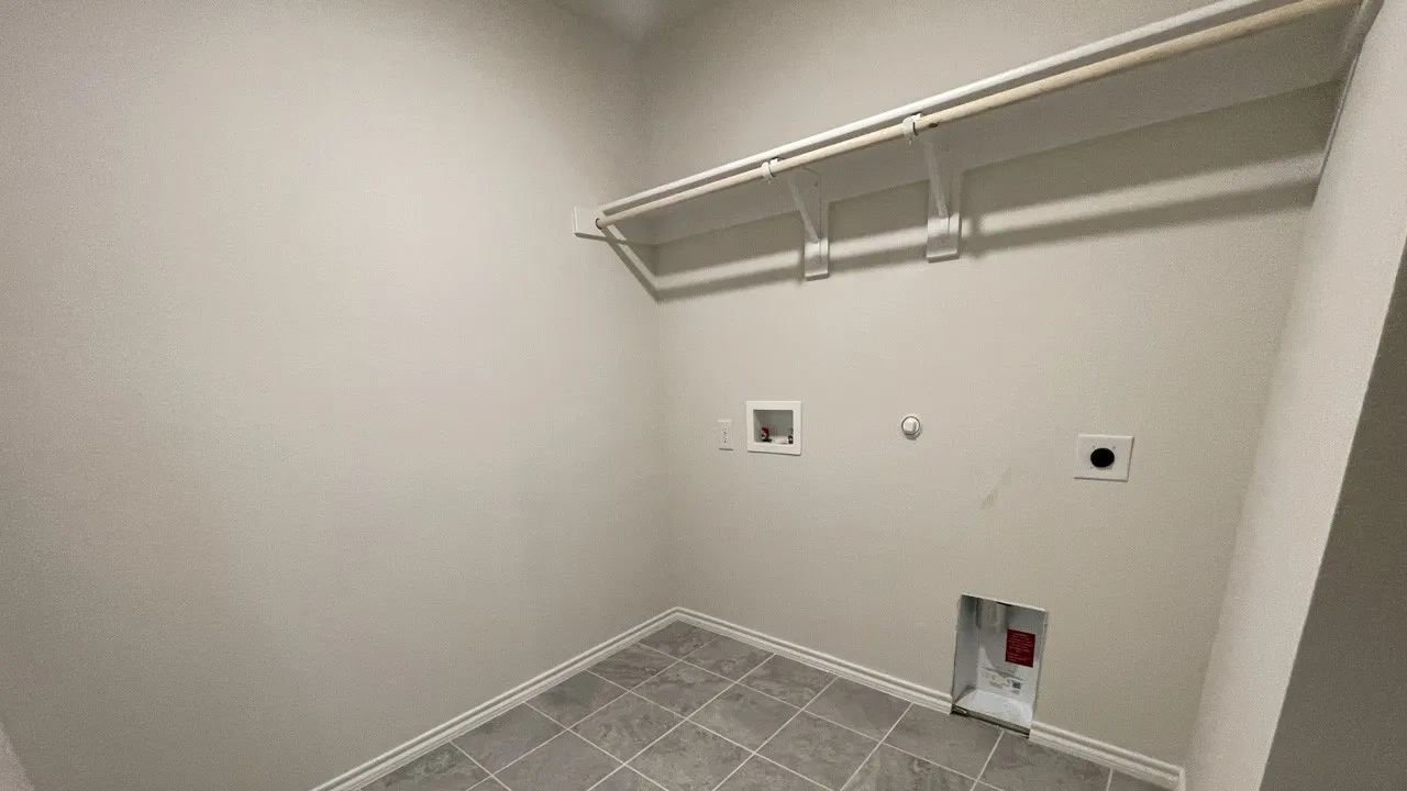 Utility room with tile flooring, light-toned walls, and built-in shelving