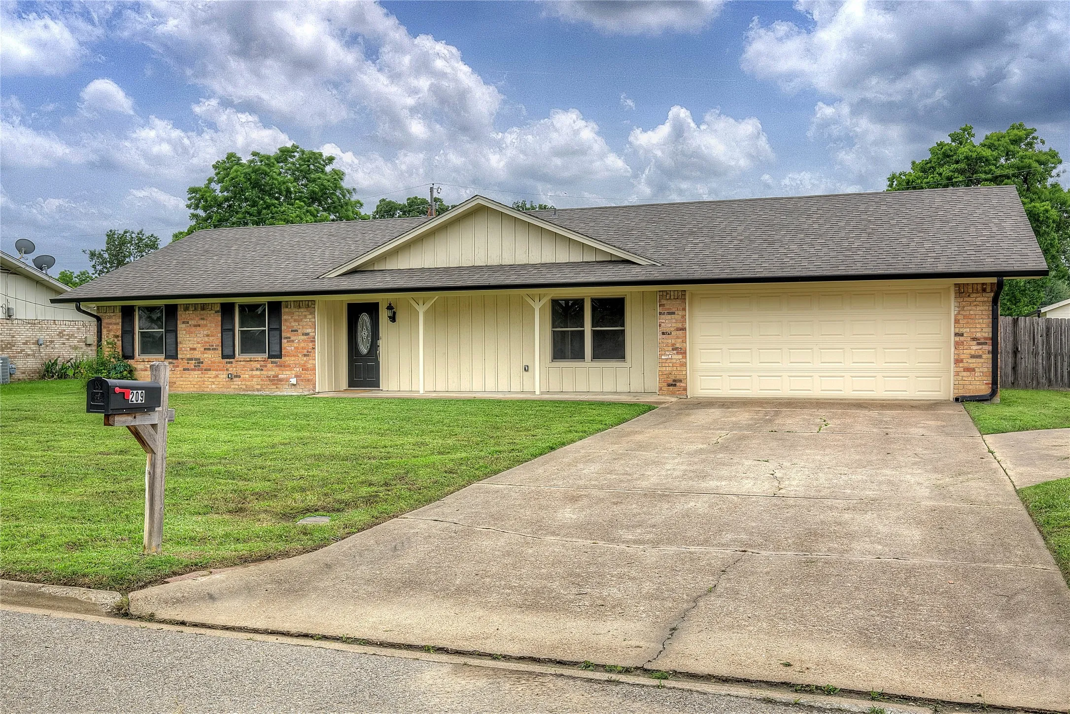 Brick home on a quiet street with a large fenced lot and shaded front porch.