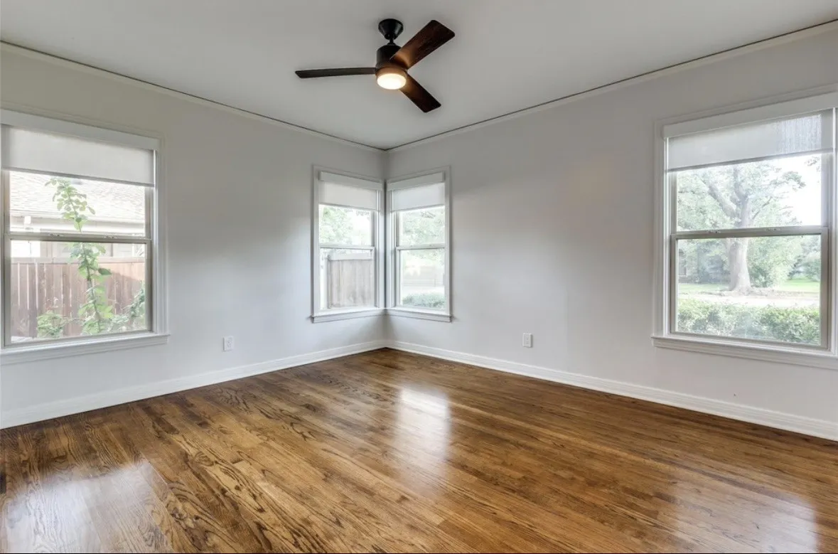 Wood-finish flooring, multiple windows, ceiling fan with integrated lighting, and crown molding
